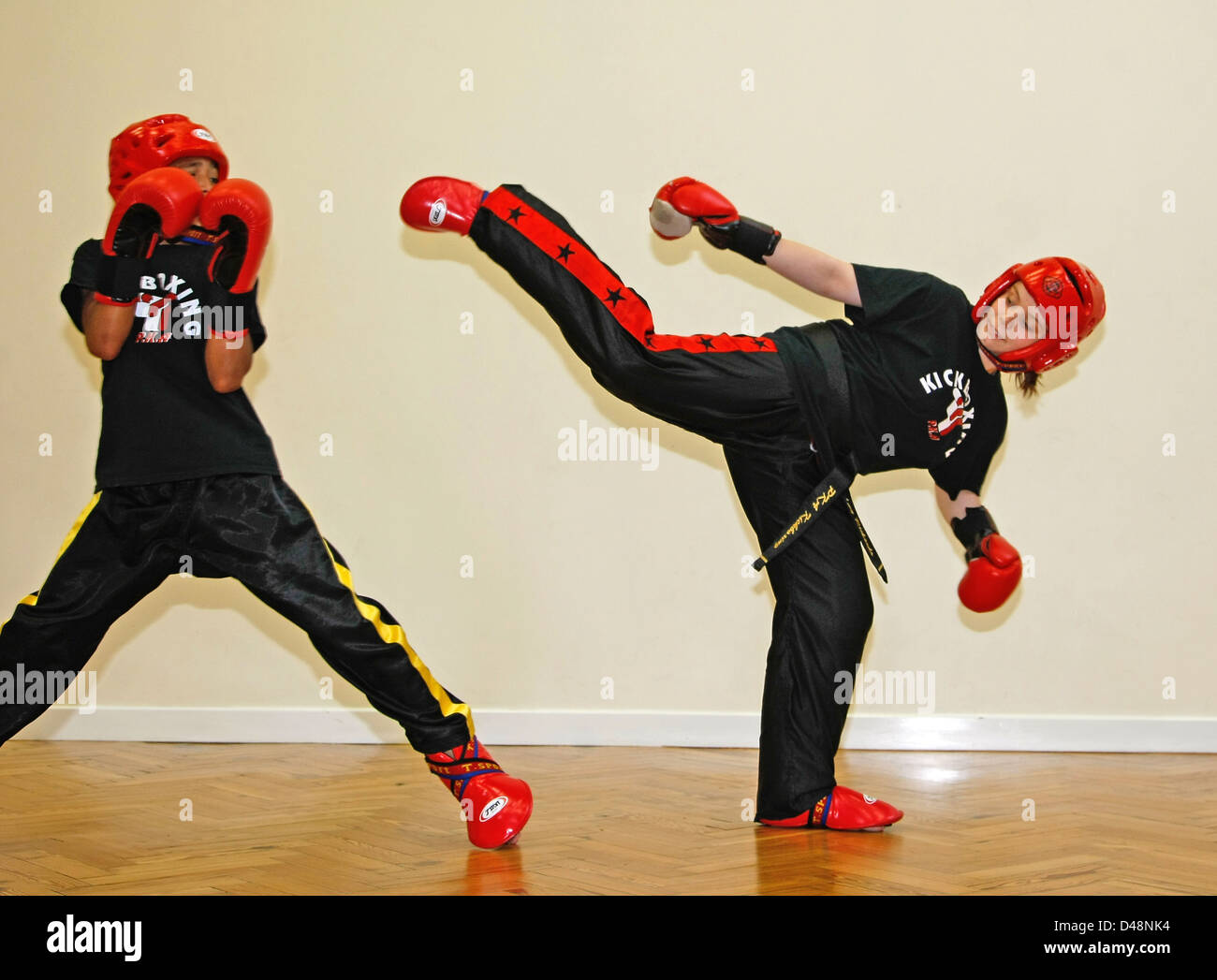 Teenage girl posed high kicking at a teenage boy during martial arts
