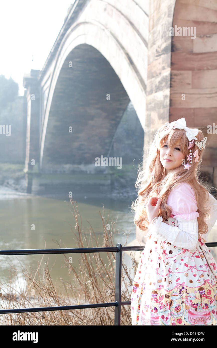 Female model in Cosplay Lolita Clothes by bridge outdoors Stock Photo