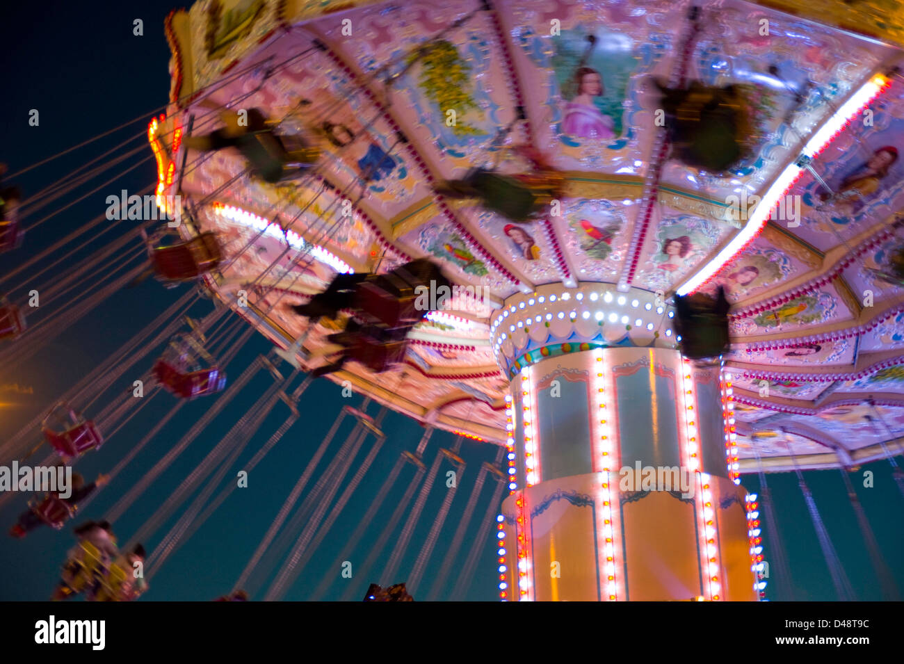 A spectacular fairground chair ride at night with people swinging ...