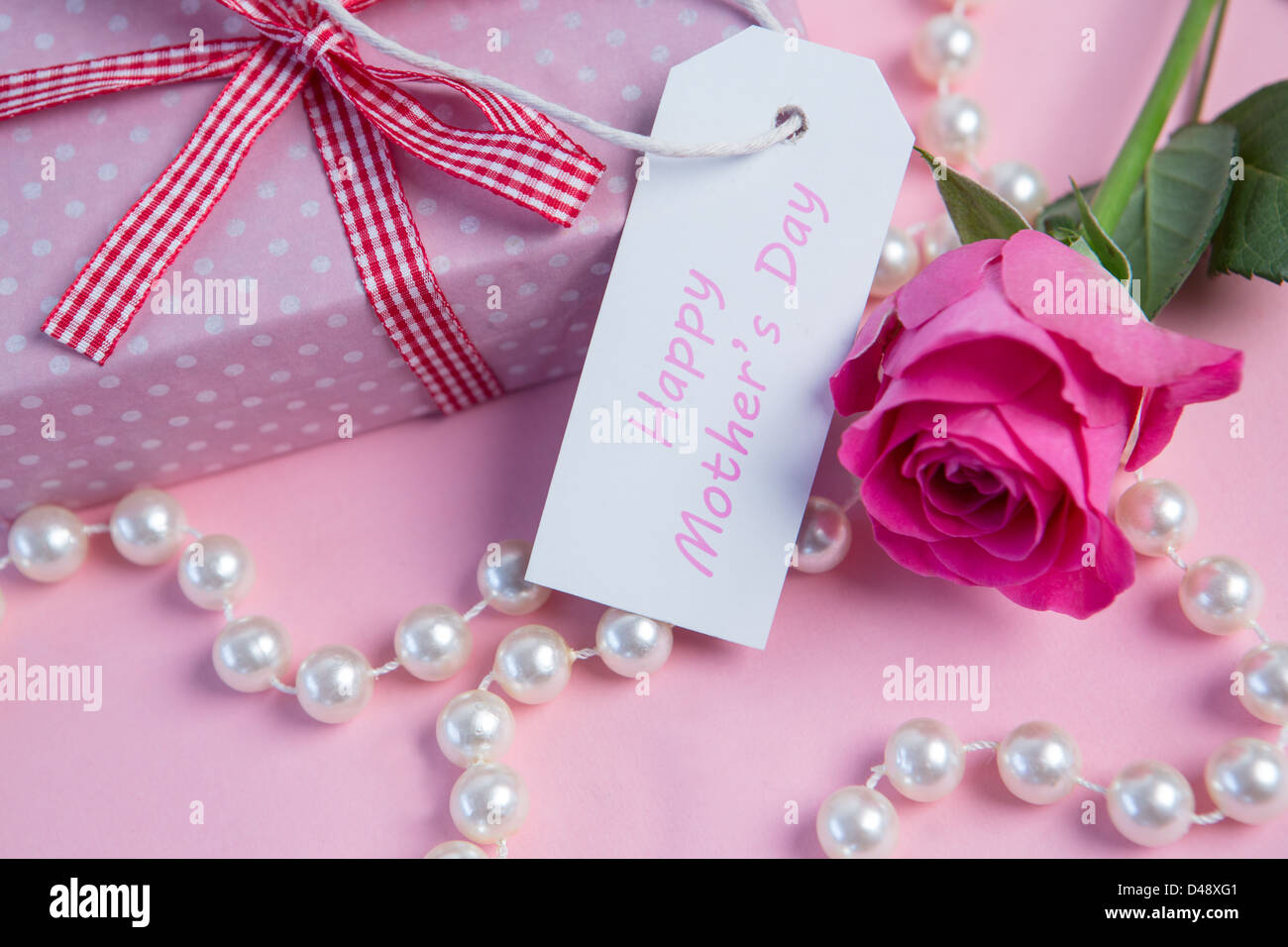 Pink rose with gift and string of pearls and tag for mothers day Stock Photo