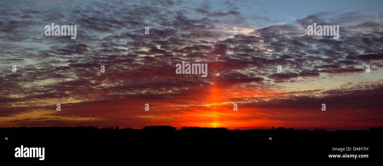 Panoramic shot of interesting looking sunset with big orange beam of light on the sky. Stock Photo
