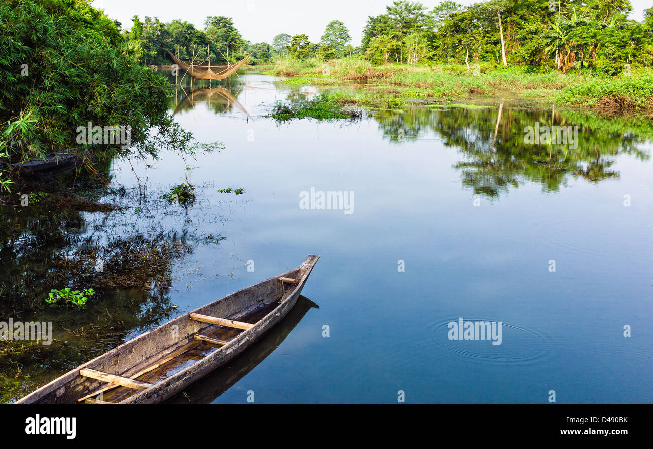 Leaking wooden boat in lagoon with Chinese fishing net on Majuli island, Assam, north east India. Stock Photo