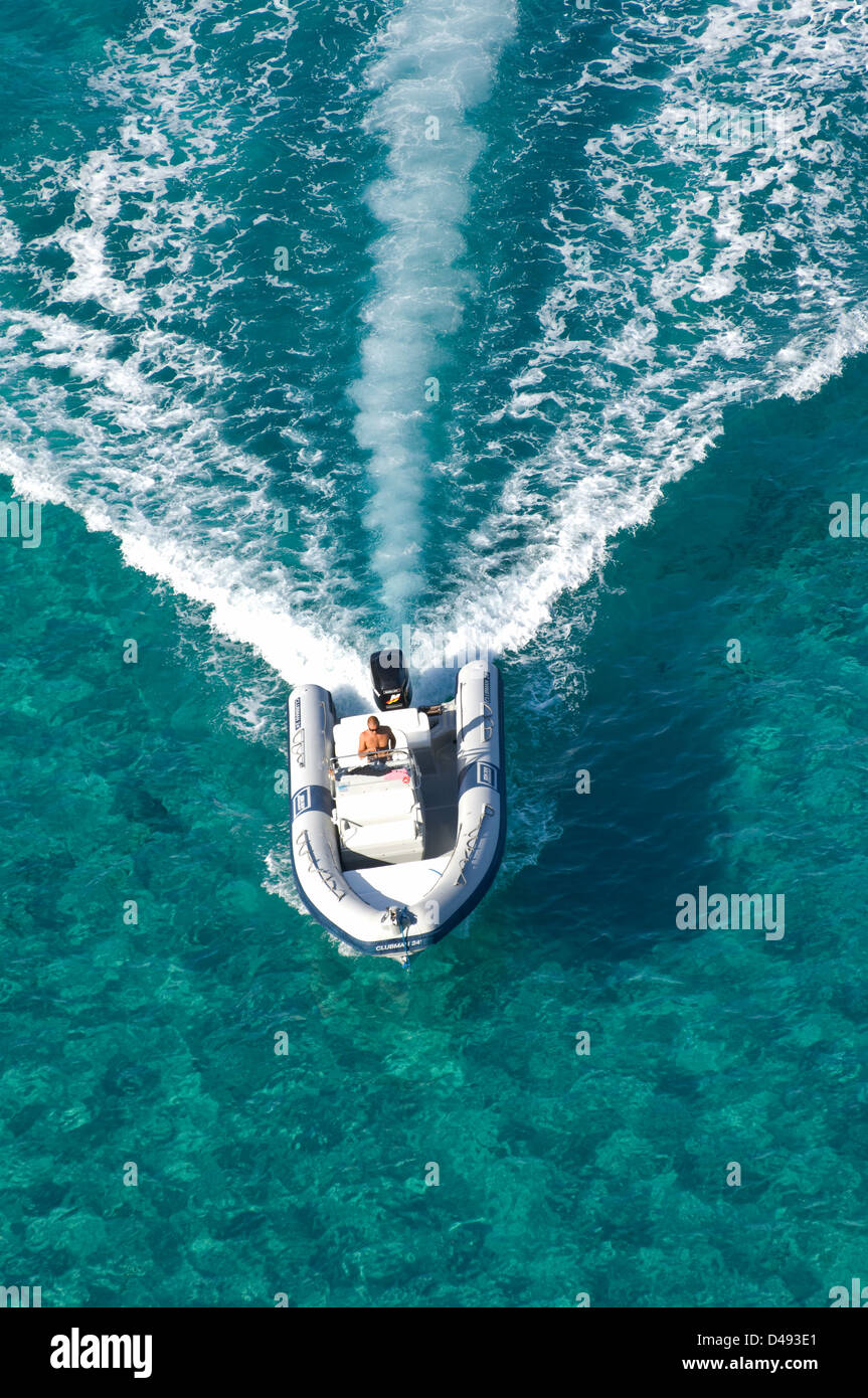 Areal view of a guy sailing a fast motorboat on the waters of the sea near Cala Luna beach, Cala Gonone, Dorgali Sardinia, Italy Stock Photo