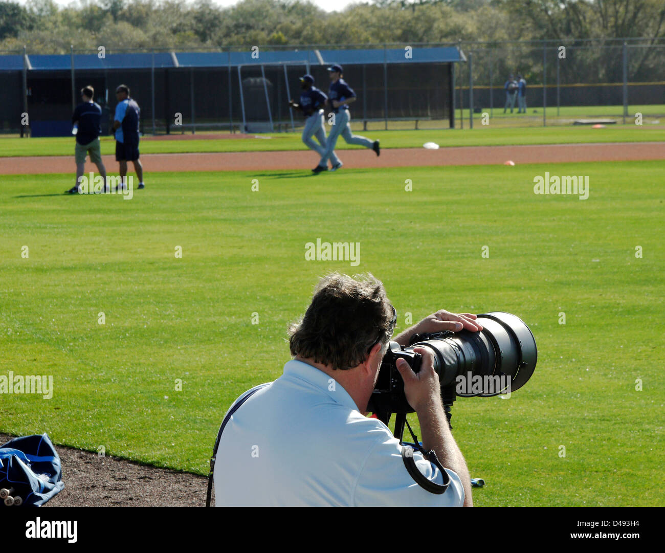 Sports photographer using long telephoto lens focuses on players during baseball spring training in Florida. Stock Photo