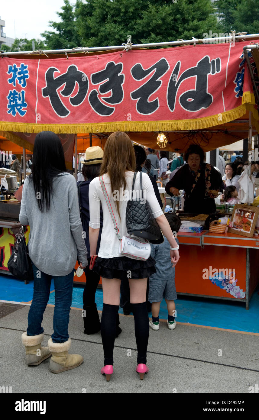 Two young Japanese ladies waiting in line at a festival roten stand for a yakisoba meal. Stock Photo