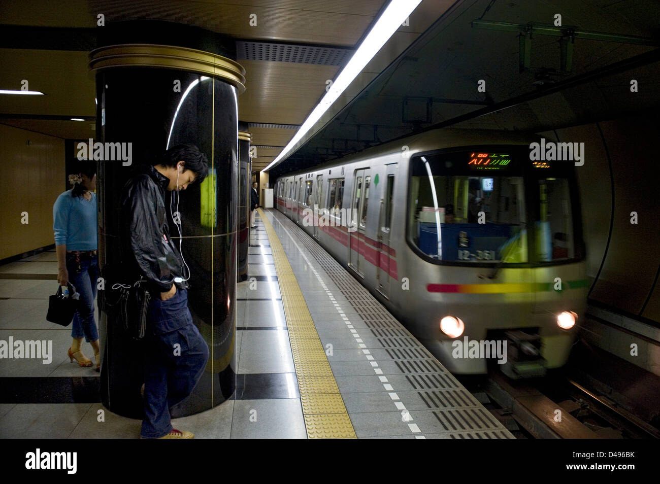 Passengers waiting for subway train arriving at underground platform in the Tokyo Metro railway transportation system in Japan Stock Photo