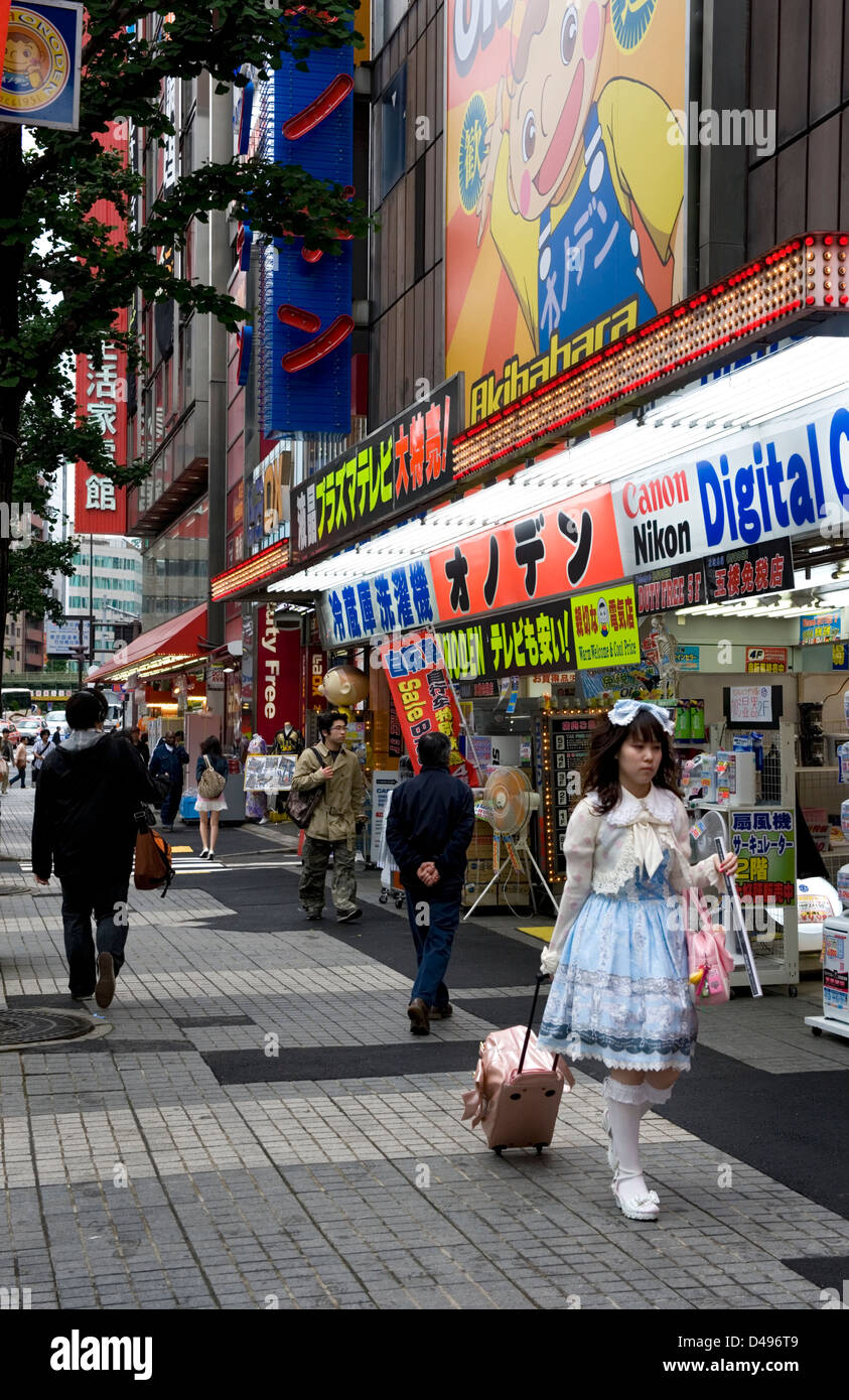 A girl wearing lolita style clothing walks down the sidewalk in the consumer electronics district of Akihabara, Tokyo. Stock Photo