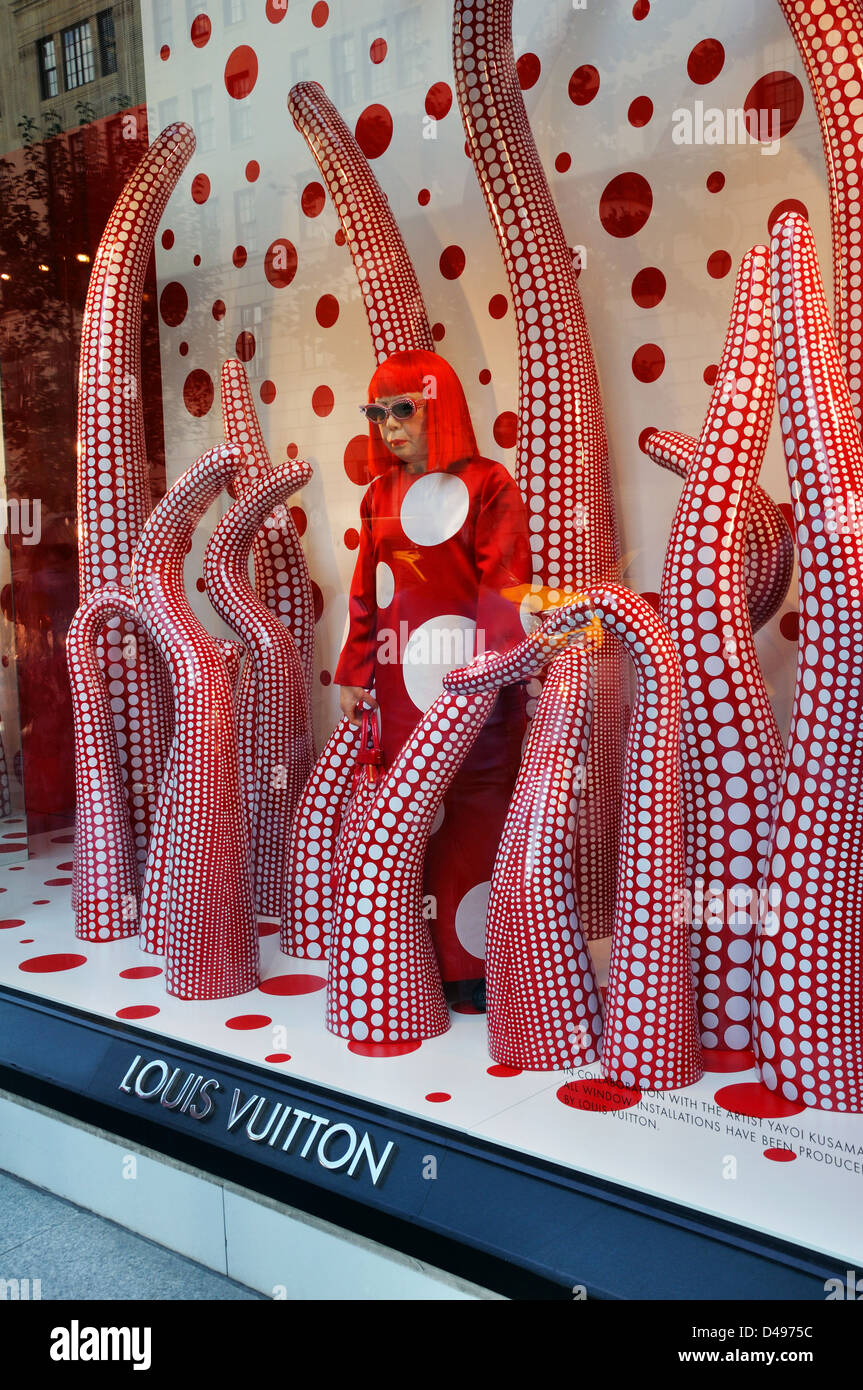 People use their smartphones to take pictures of the Yayoi Kusama robot  painting spots on the window of the luxury retailer Louis Vuitton's Fifth  Avenue store, New York, NY, January 9, 2023.