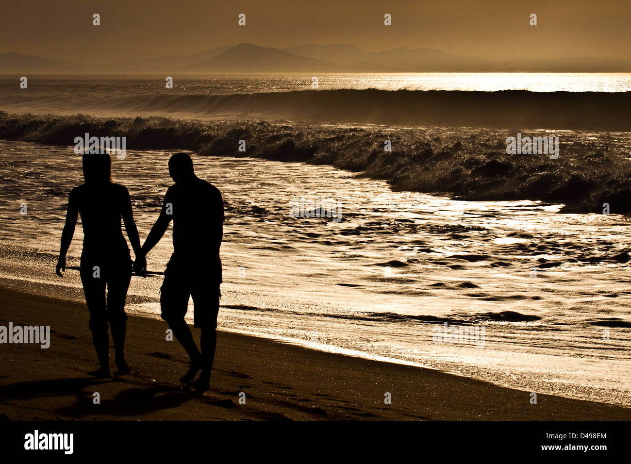 Couple walking along the beach holding hands at sunset in the south-west of France. Stock Photo
