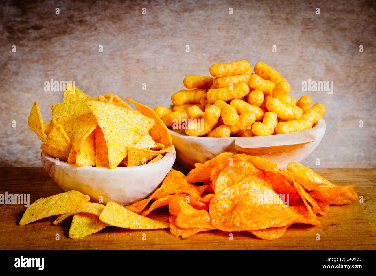 Chips, nachos and curls snacks on a wooden background Stock Photo