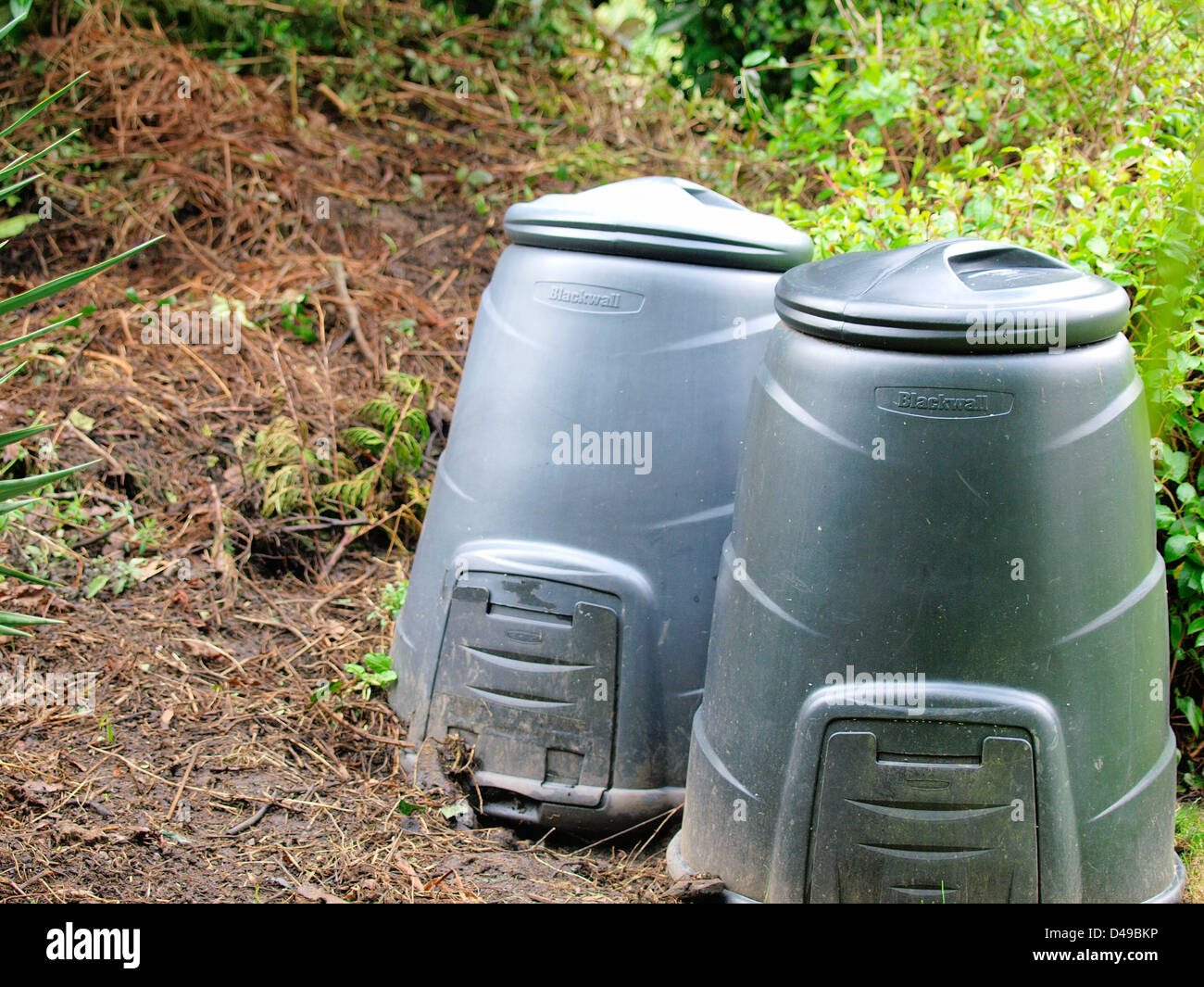 Two compost bins standing in overgrown garden Stock Photo Alamy