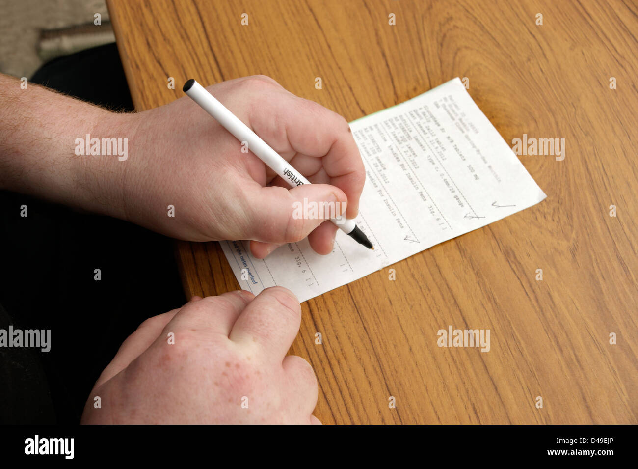 Man filling in form requesting repeat prescription / prescriptions