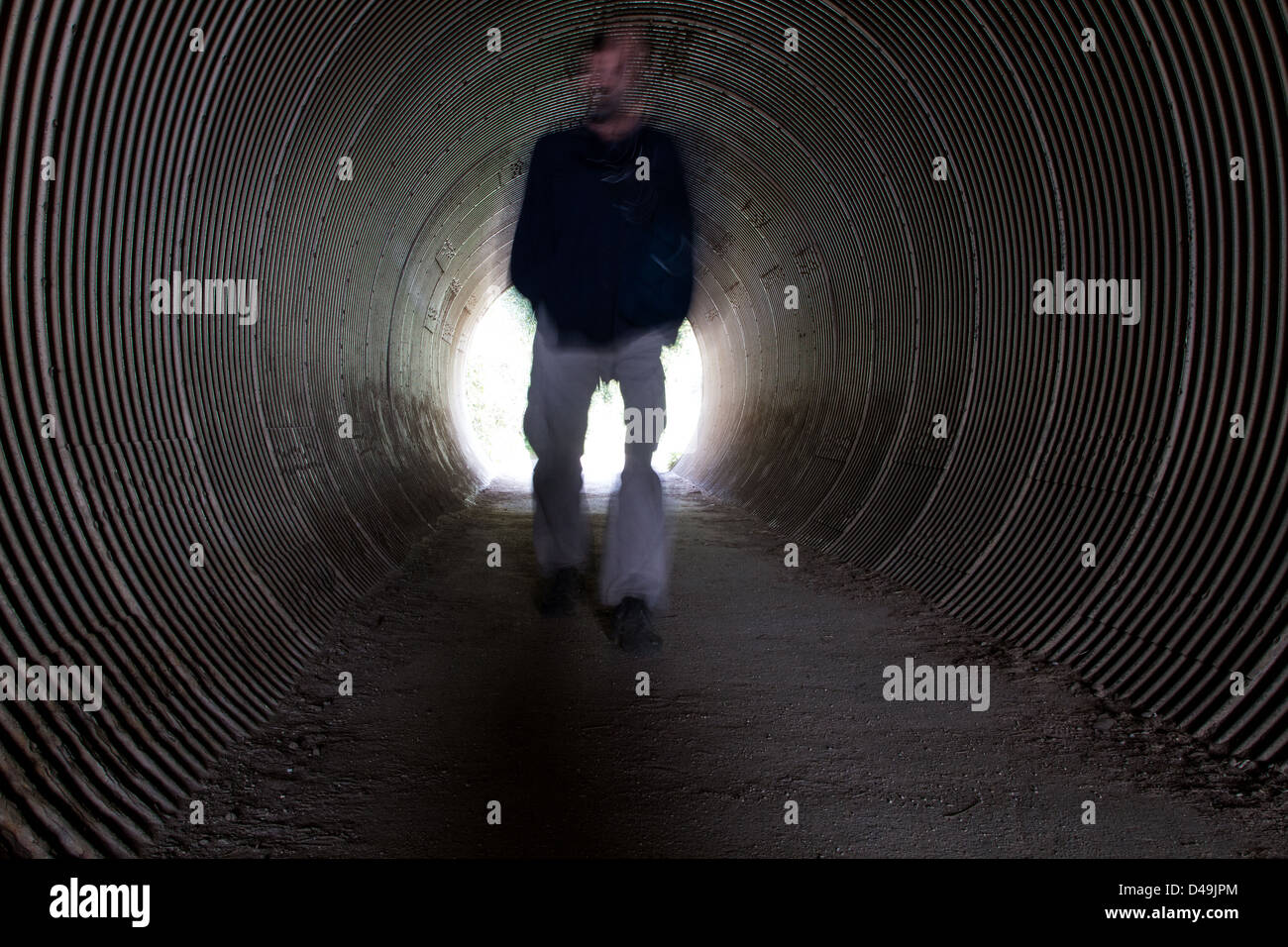 A single man walking through a tunnel into the light Stock Photo - Alamy