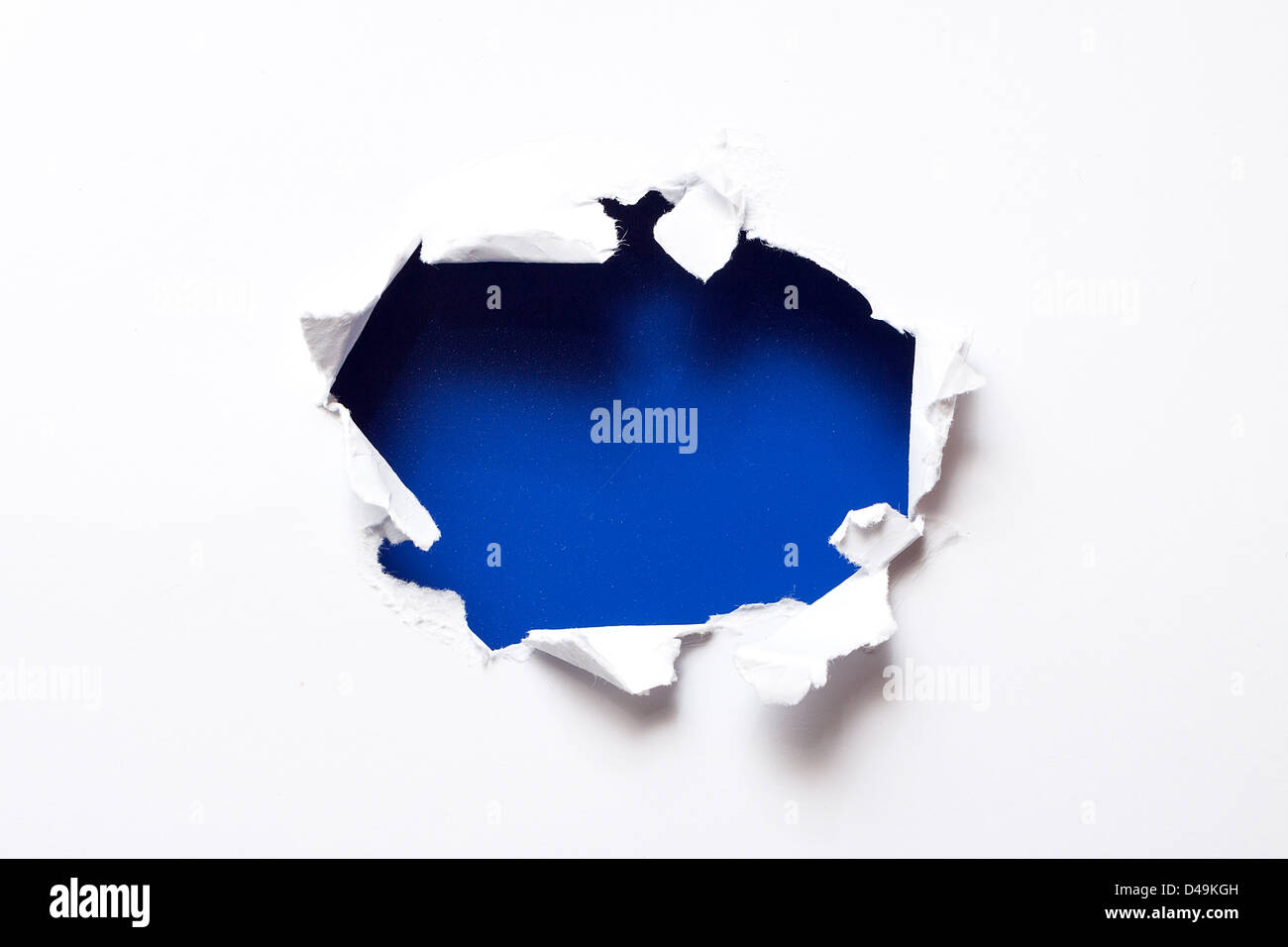 Breakthrough paper hole with blue textured background. Stock Photo