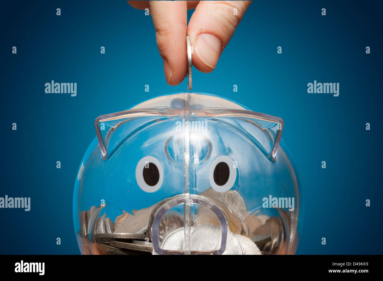 Saving, male hand putting a coin into piggy bank Stock Photo - Alamy