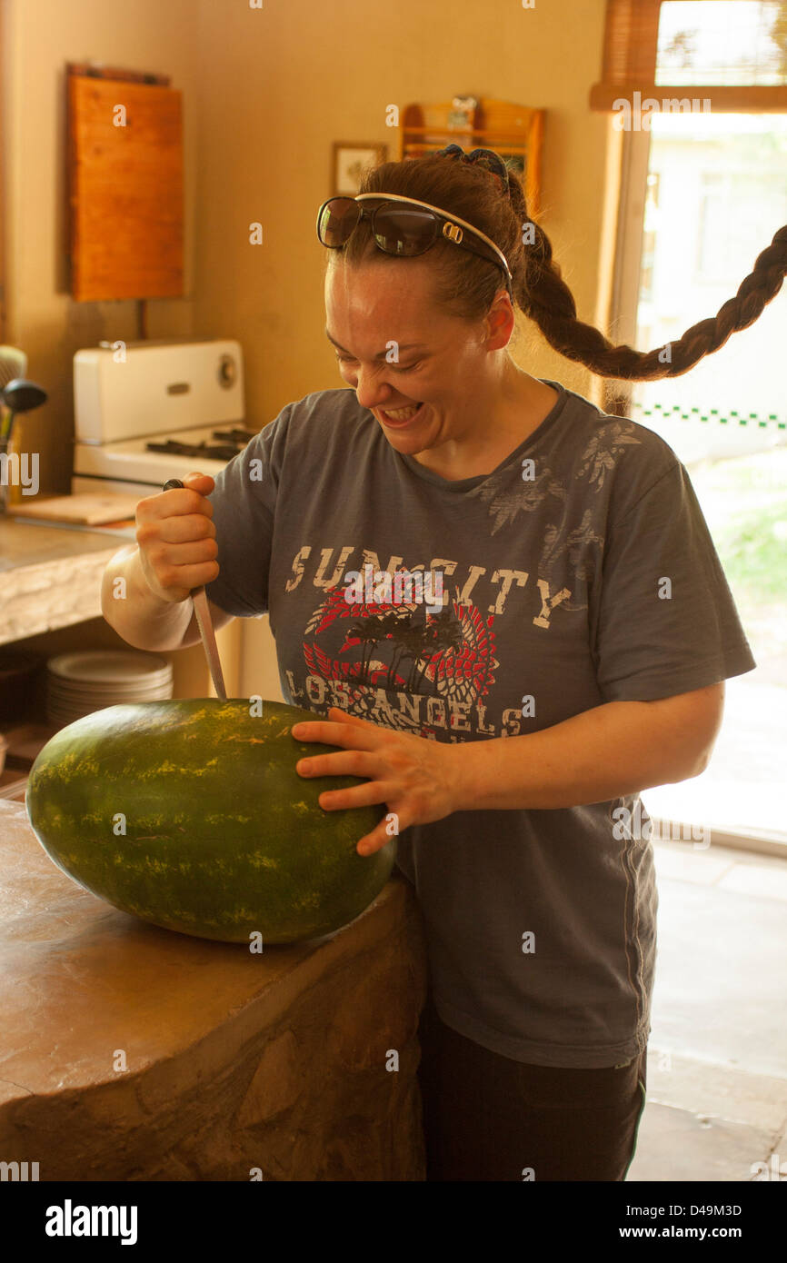Attack of the watermelon  with a knife by girl with crazed maniacal crazy weird funny  psychopathic look. Stock Photo