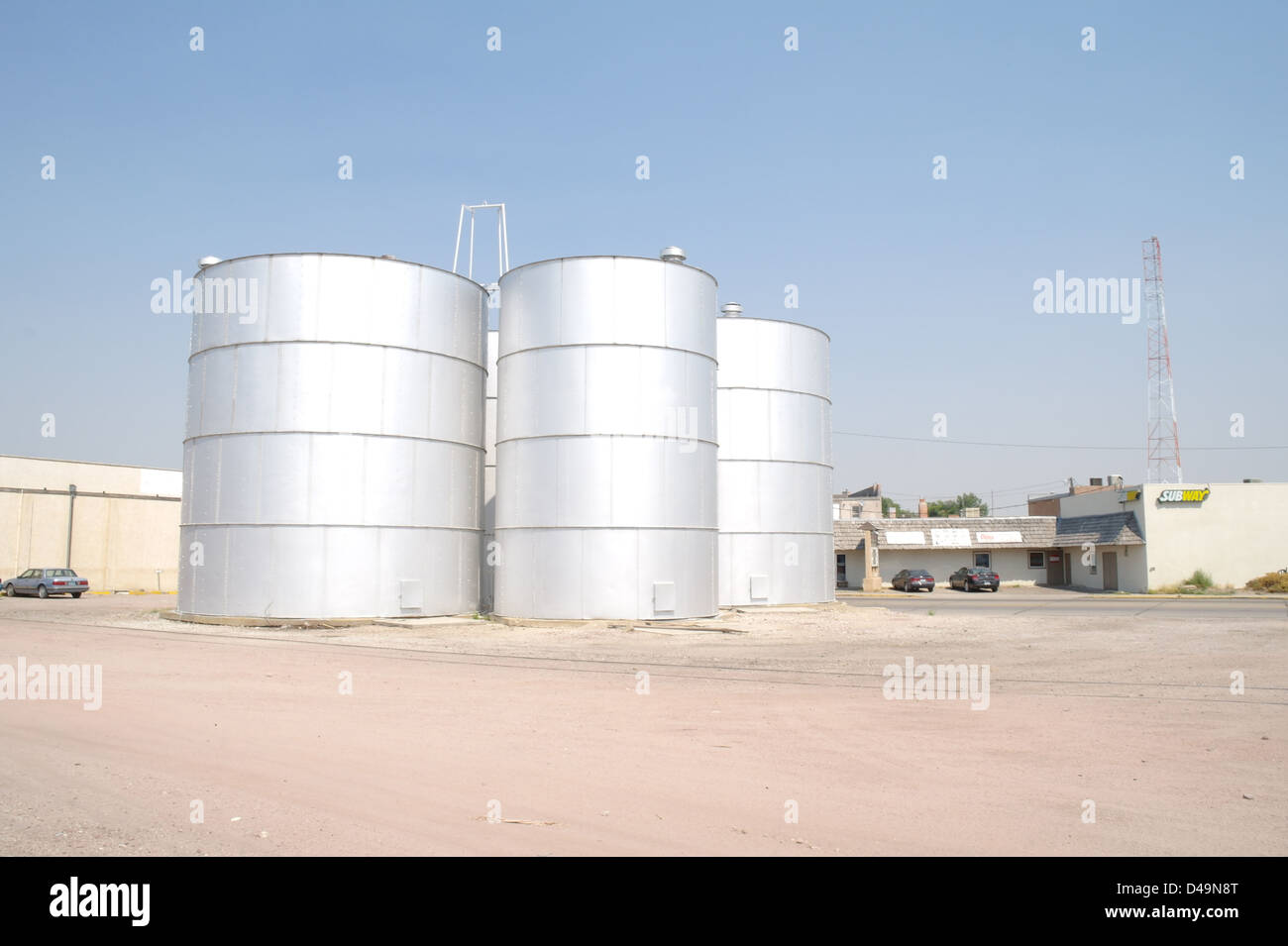 Blue sky view 4 tall silver metal grain elevators silos, Kelley Bean Company, West Valley Road, Torrington, Wyoming, USA Stock Photo