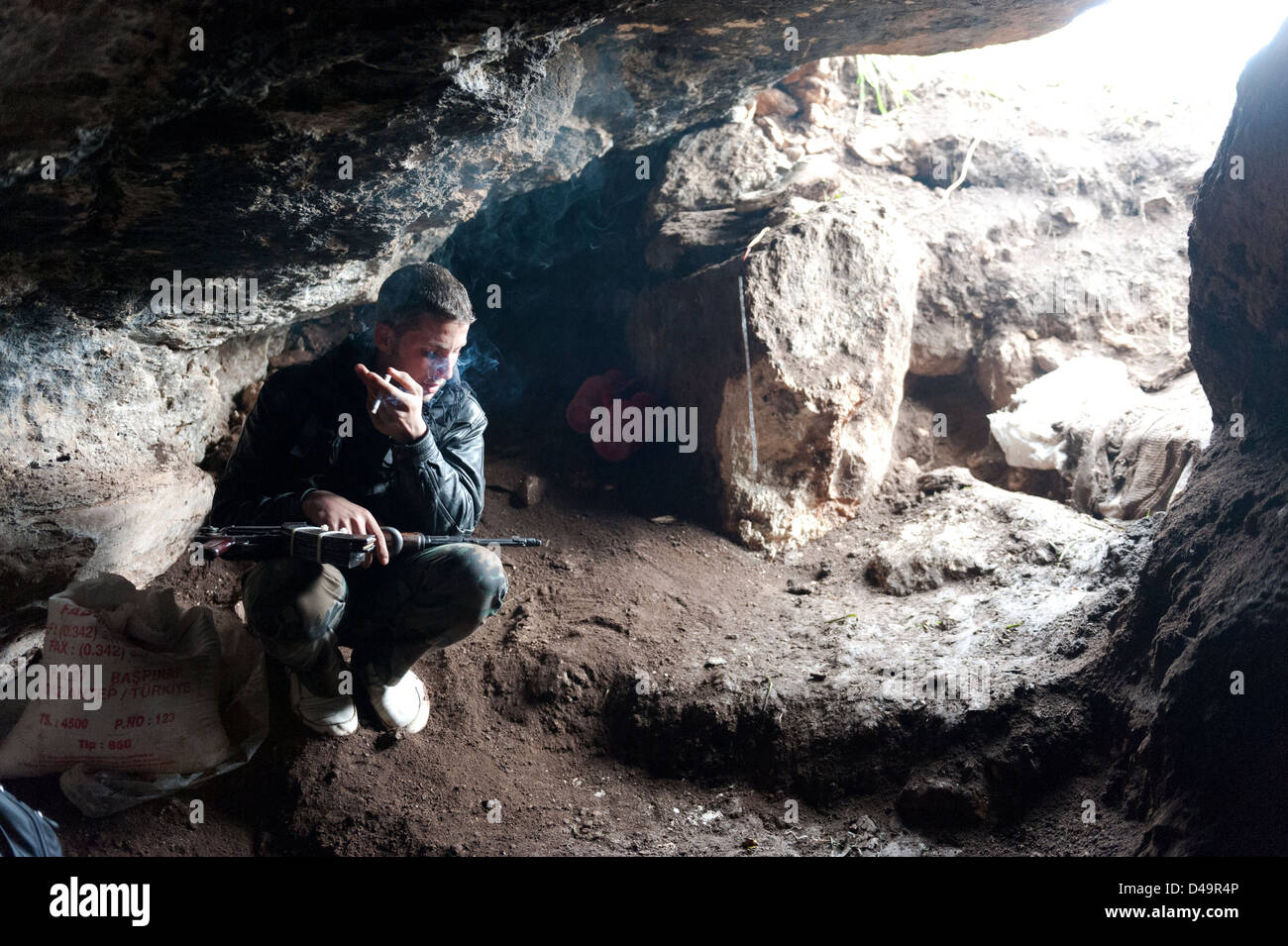 A soldier of the Free Syrian Army is guarding the entrance to a cave, Assaharia, Syria Stock Photo
