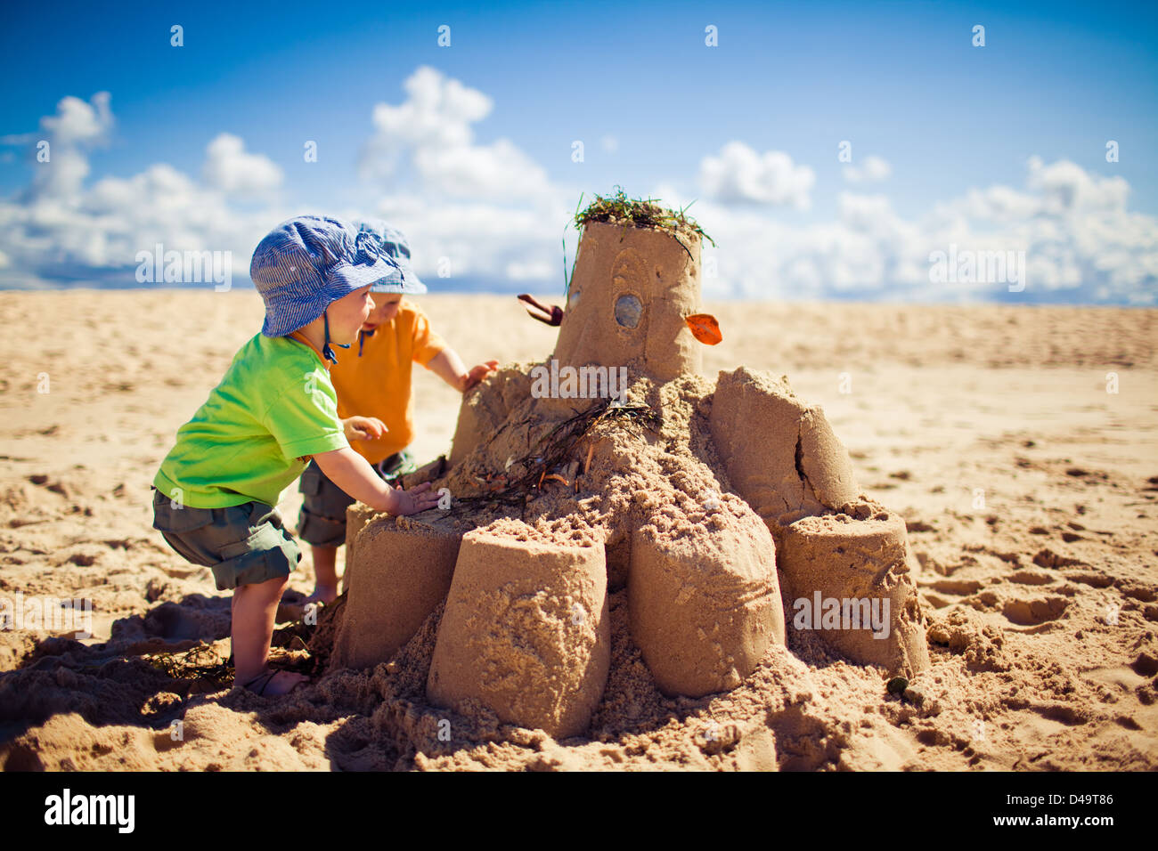 Two little boys building large sandcastle on the beach Stock Photo