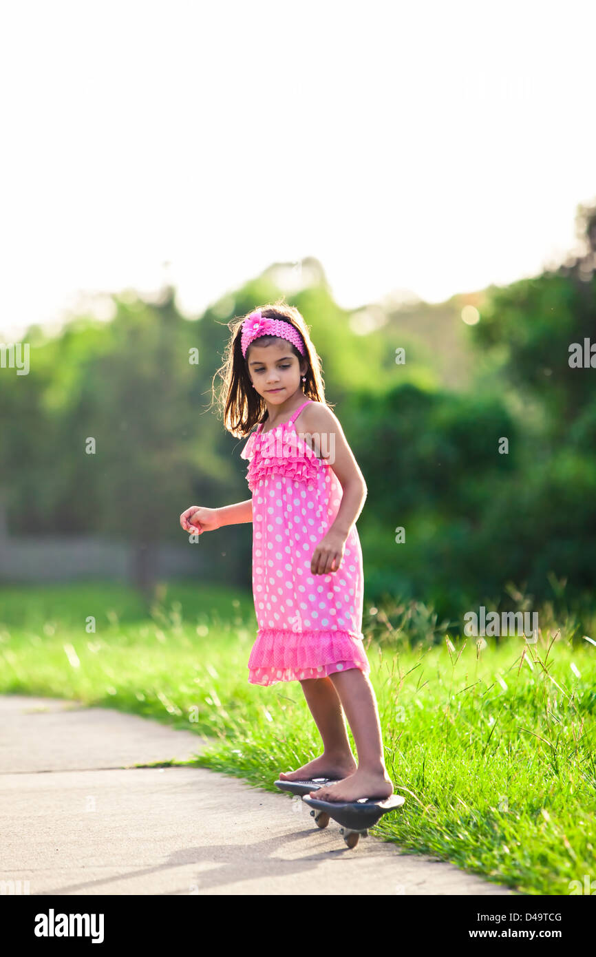 Young girl in pink dress riding on skateboard outdoors Stock Photo Alamy