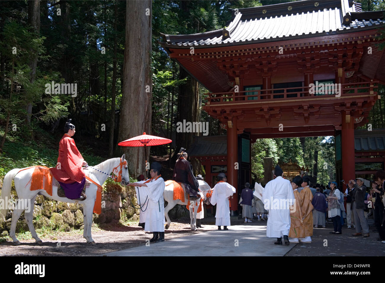 Festival procession moves through a gate at Futarasan Shrine for the annual spring Shunki Reitaisai in Nikko, Tochigi, Japan. Stock Photo