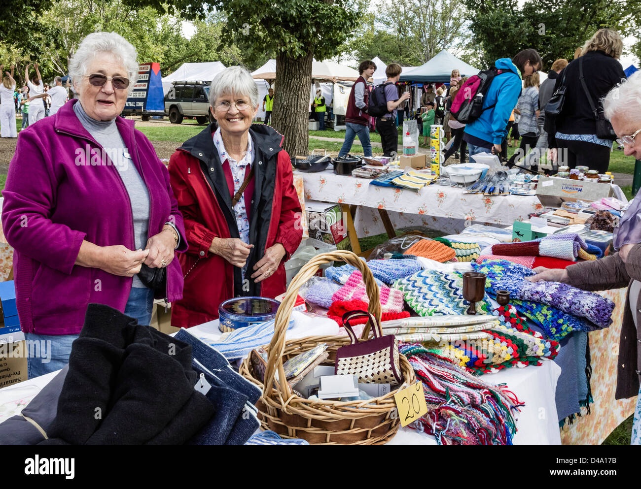 Two elderly ladies at a market stall proud of their handcrafted items