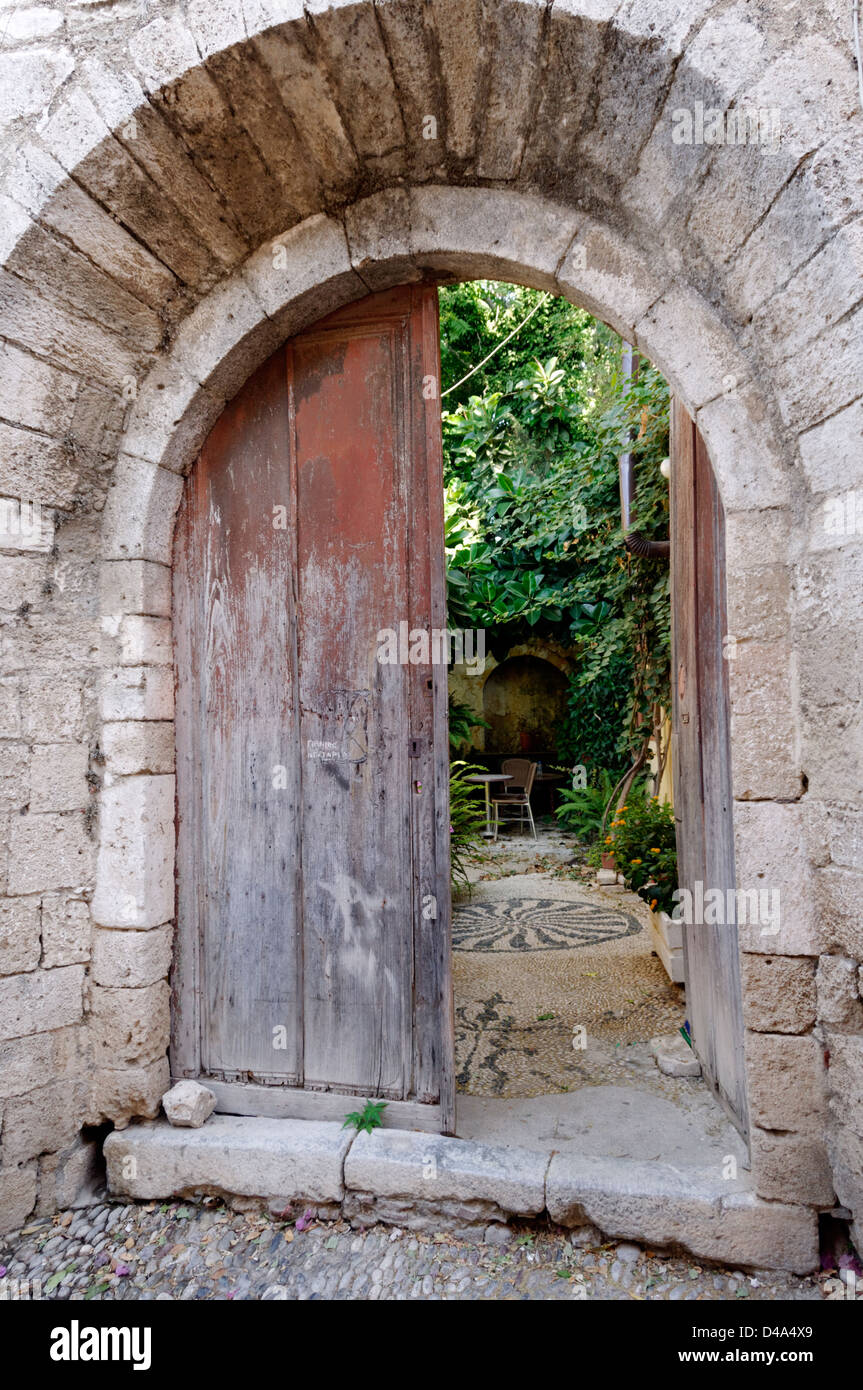 Rhodes. Greece. Picturesque view of an old stone building with an arched doorway that opens up into an inner garden courtyard. Stock Photo