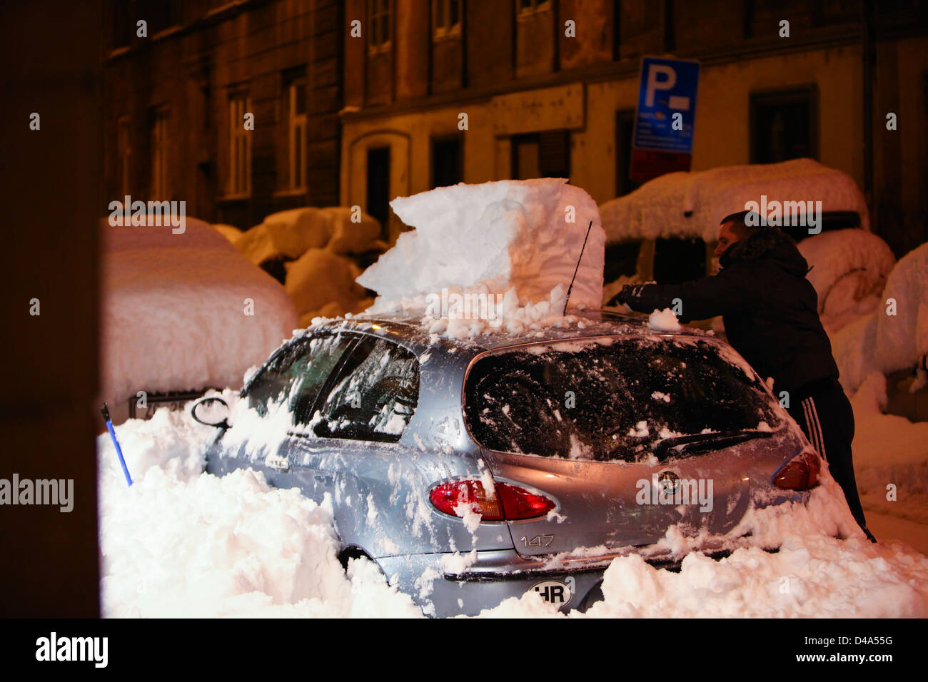 A man removing snow from his car after heavy snow fall. Stock Photo