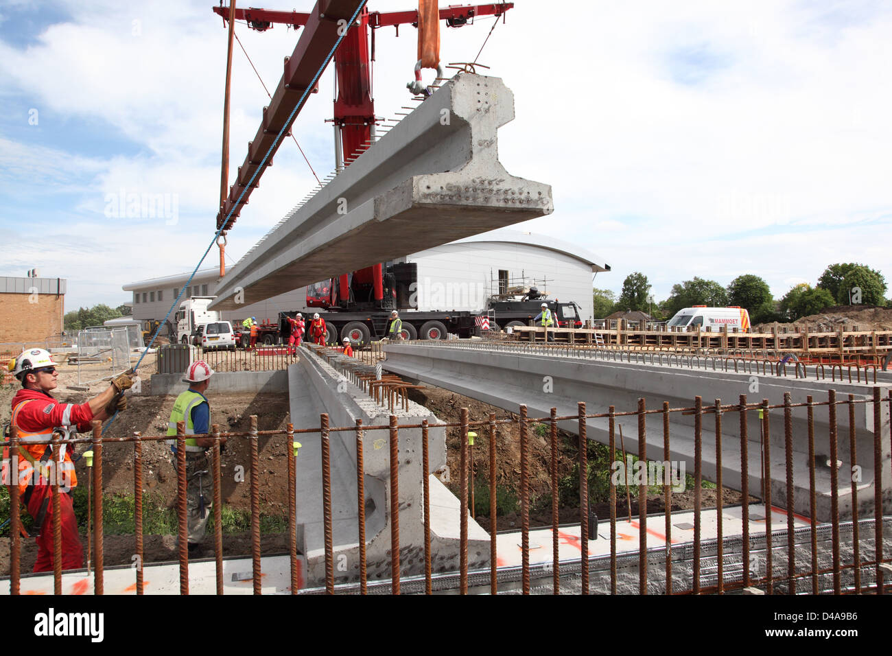 17m long pre-stressed concrete beams are lowered into place to support a new road bridge spanning a river culvert in Woking, UK Stock Photo