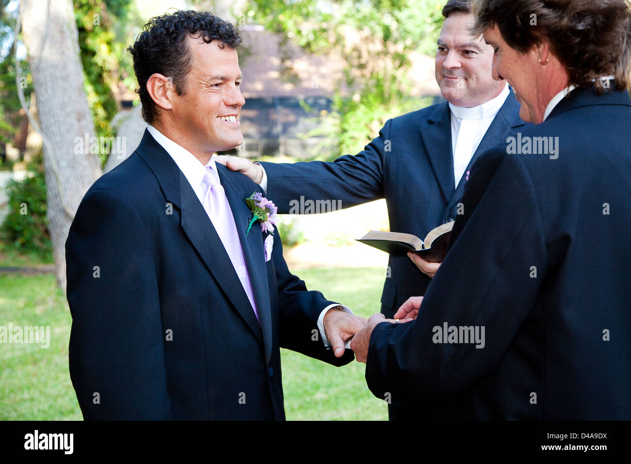 Gay couple exchanges rings during their wedding ceremony.  Stock Photo