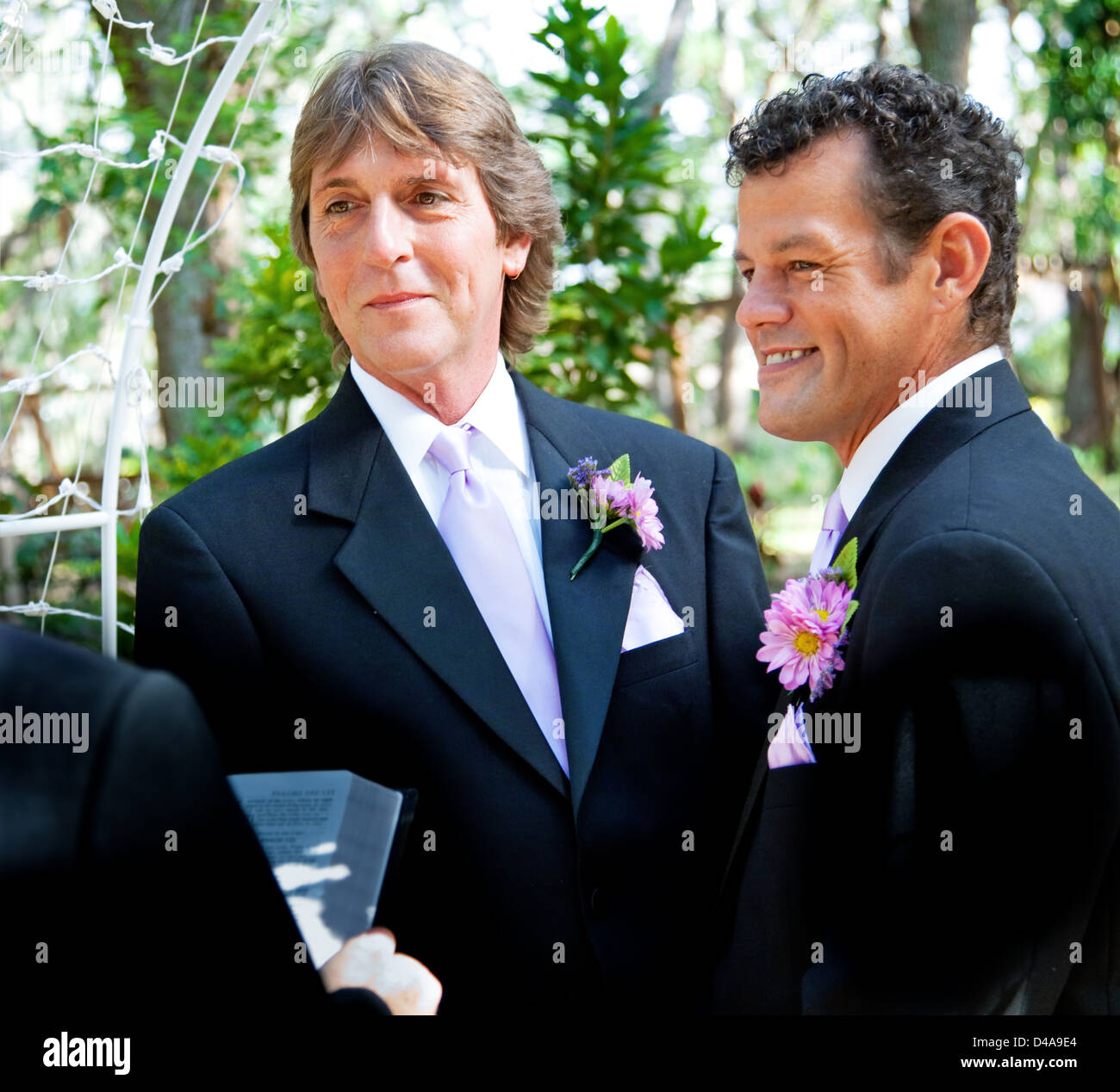 Handsome gay couple getting married in outdoor ceremony. Stock Photo