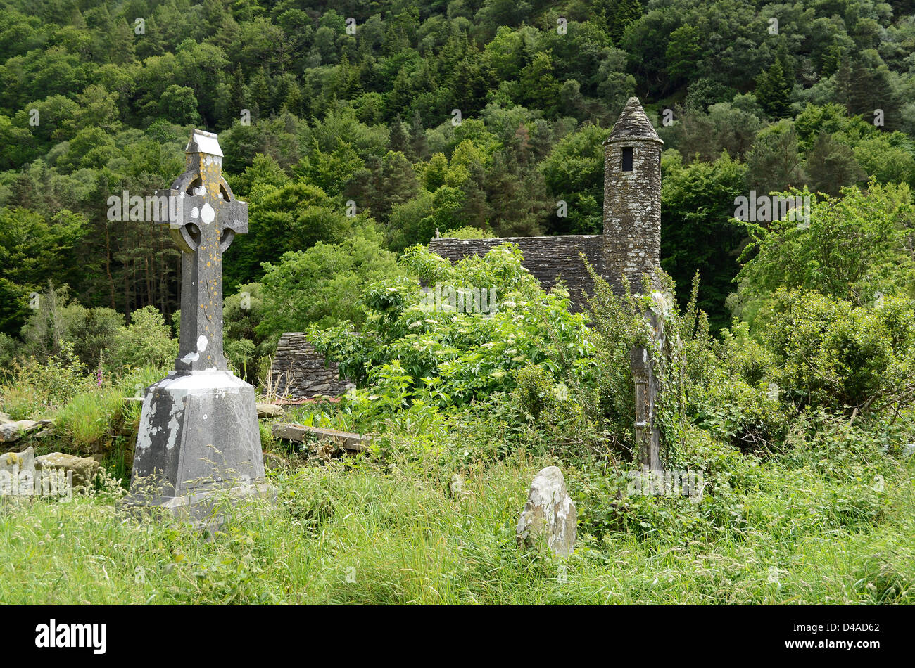 A celtic cross on the overgrown graveyard next to the medieval church of St. Kevin at the monastic heritage site Glendalough. Stock Photo