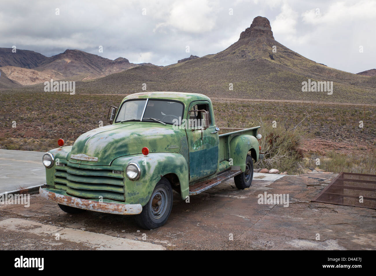 An old pickup parked by Route 66 next to a mountain Stock Photo