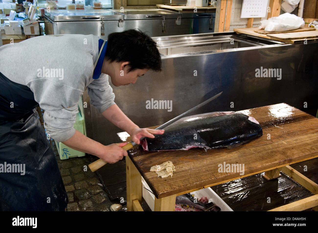 Fishmonger cuts fresh raw tuna with large sharp knife at Tsukiji