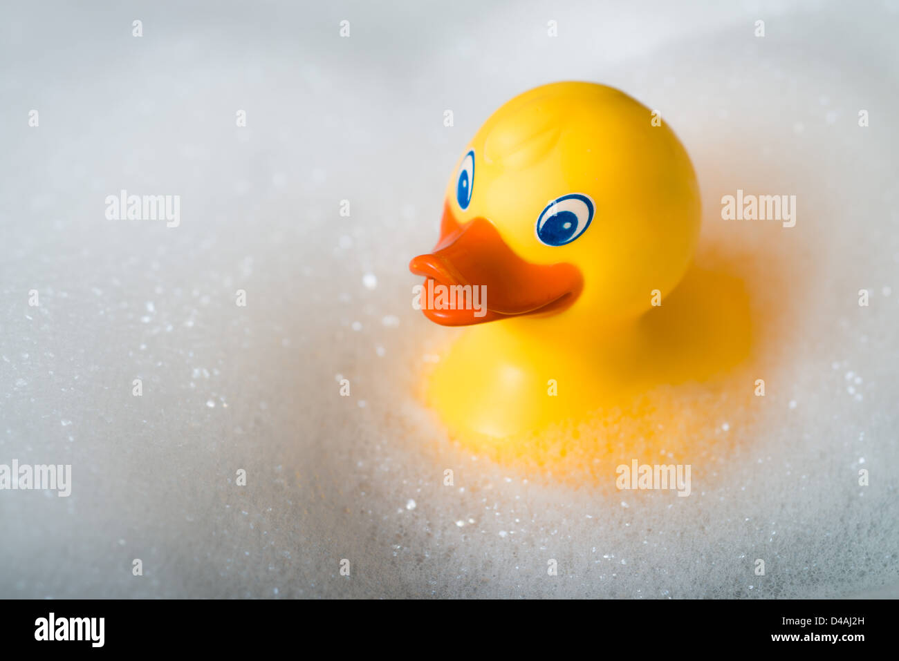 Yellow rubber duck in a bath surrounded by bubbles Stock Photo