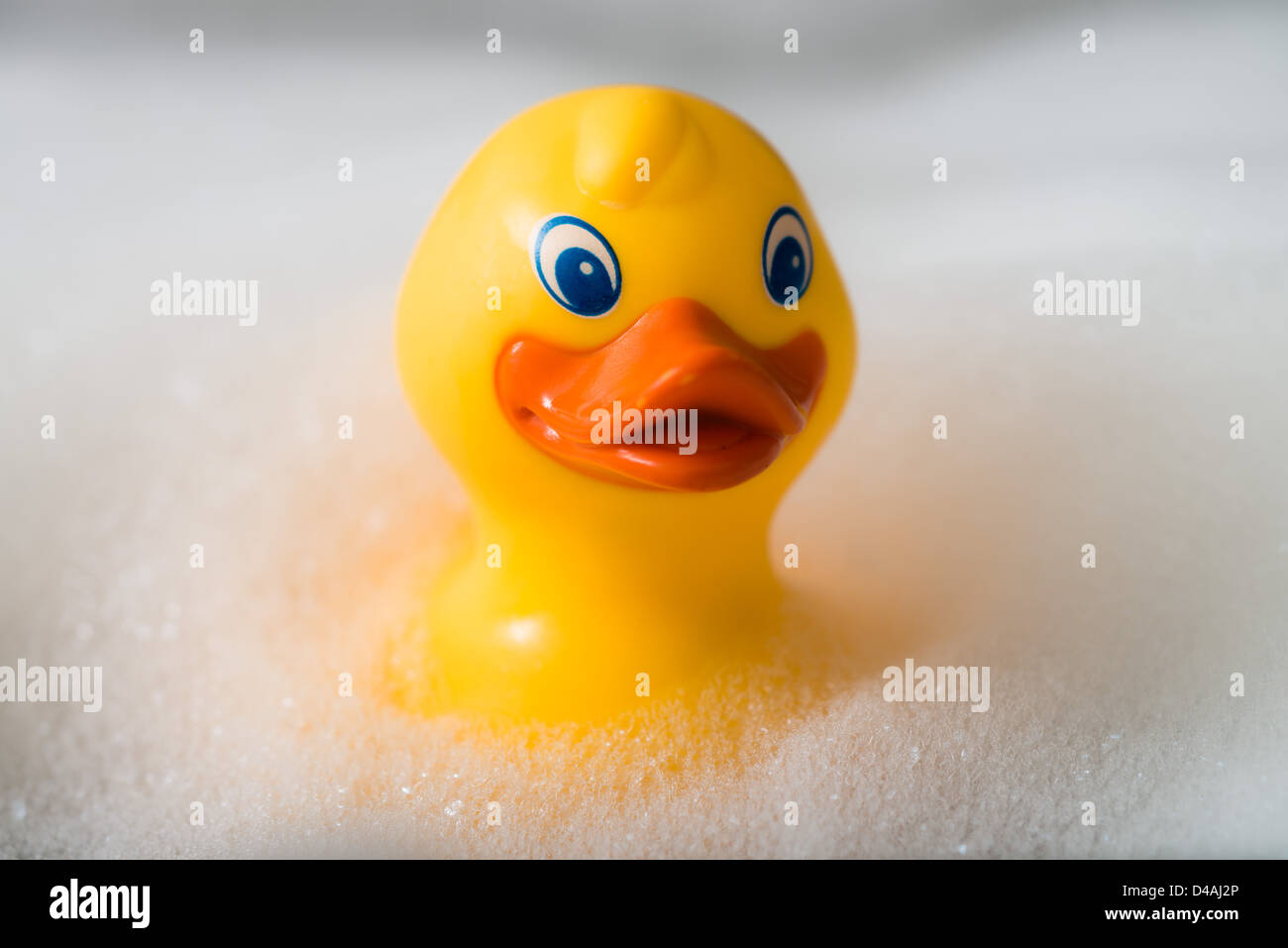 Yellow rubber duck in a bath surrounded by bubbles Stock Photo