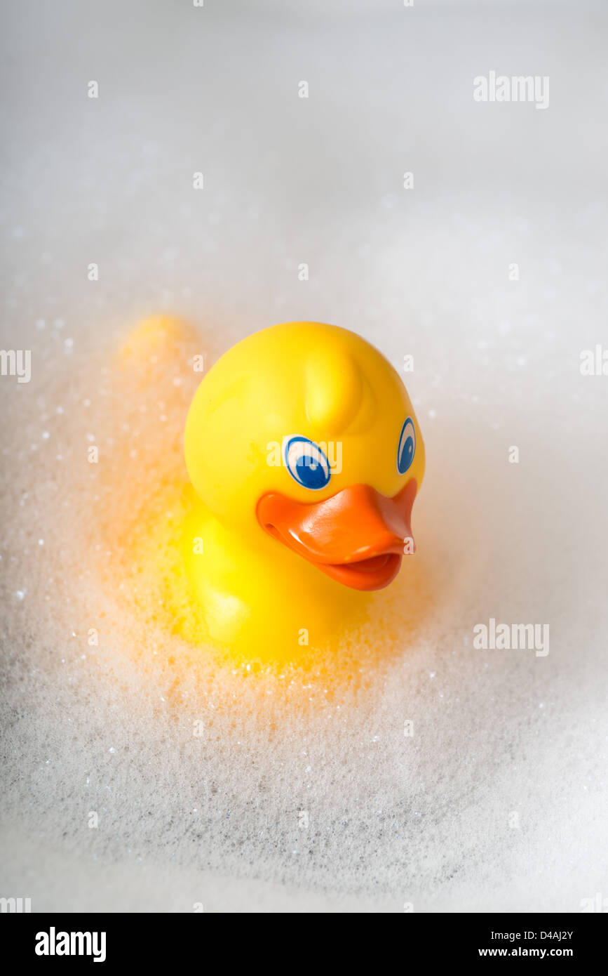 Yellow rubber duck in a bath surrounded by bubbles Stock Photo