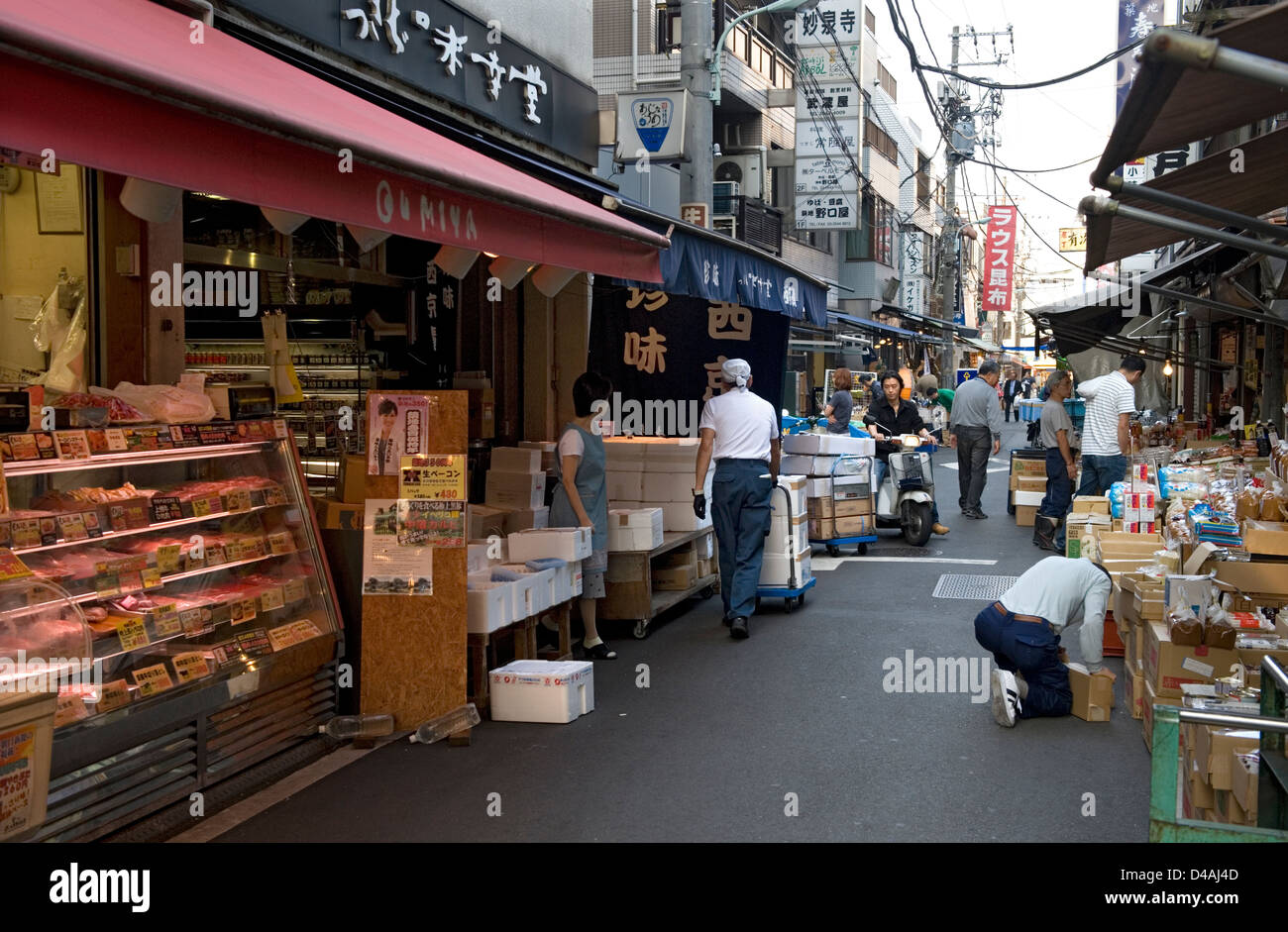 Early morning street scene lined with retail shops busy with workers and buyers moving about near Tsukiji Market in Tokyo Stock Photo