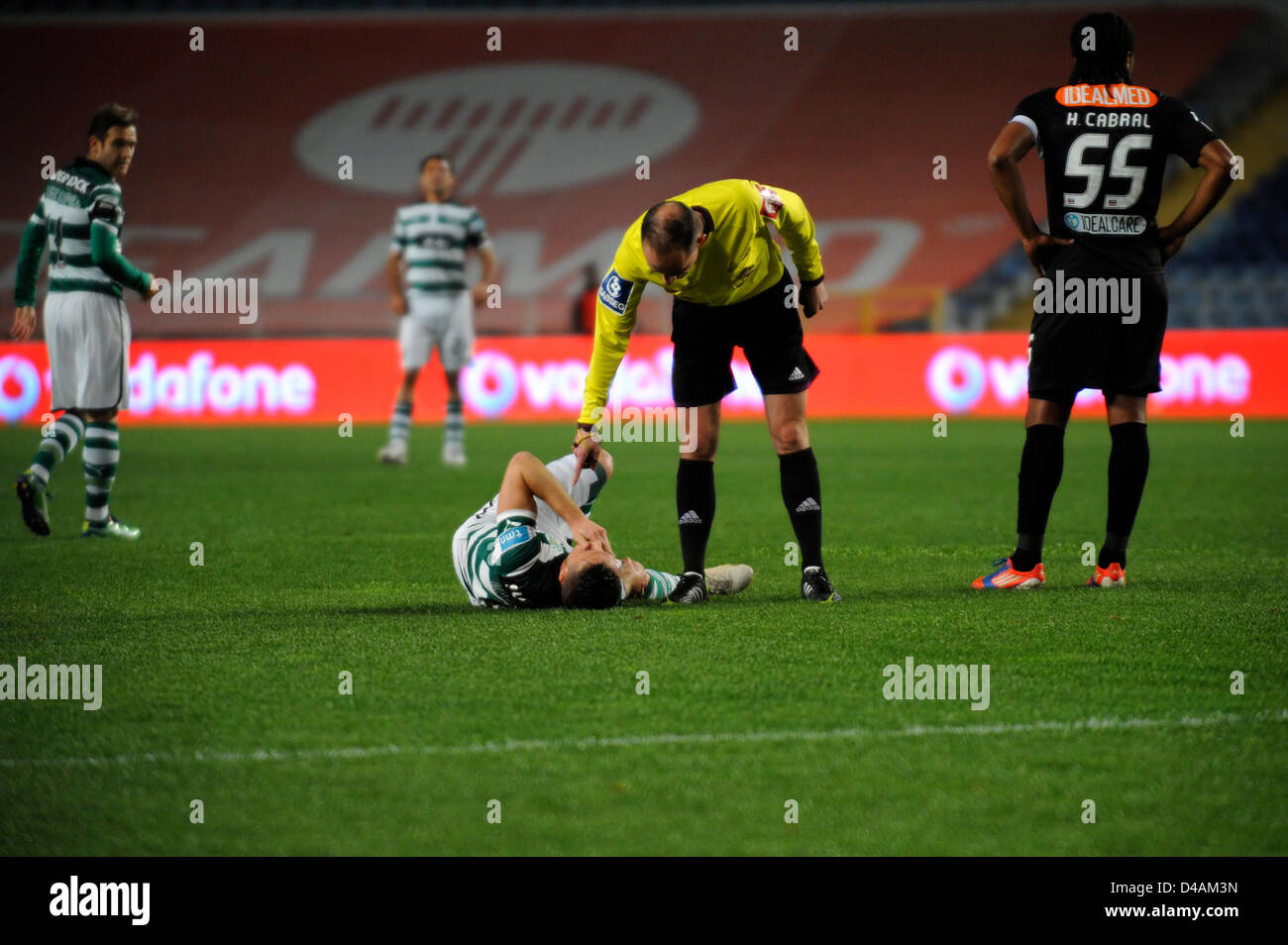Referee checks on an injured football player during a football match Stock Photo