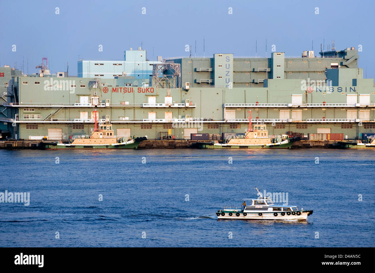 Tug boats moored beside warehouses on Yokohama Bay waterfront, Yokohama, Kanagawa, Japan Stock Photo