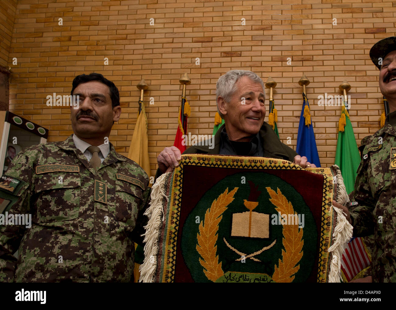 US Secretary of Defense Chuck Hagel is presented with a handmade Afghan rug with the logo of the Kabul Military Training Center by Afghan Brigadier General Aminullah Patyani, Commander of the Kabul Military Training Center March 10, 2013 in Kabul, Afghanistan. Hagel is in Afghanistan on his first trip as the Secretary of Defense visiting US troops, NATO and Afghan leaders. Stock Photo
