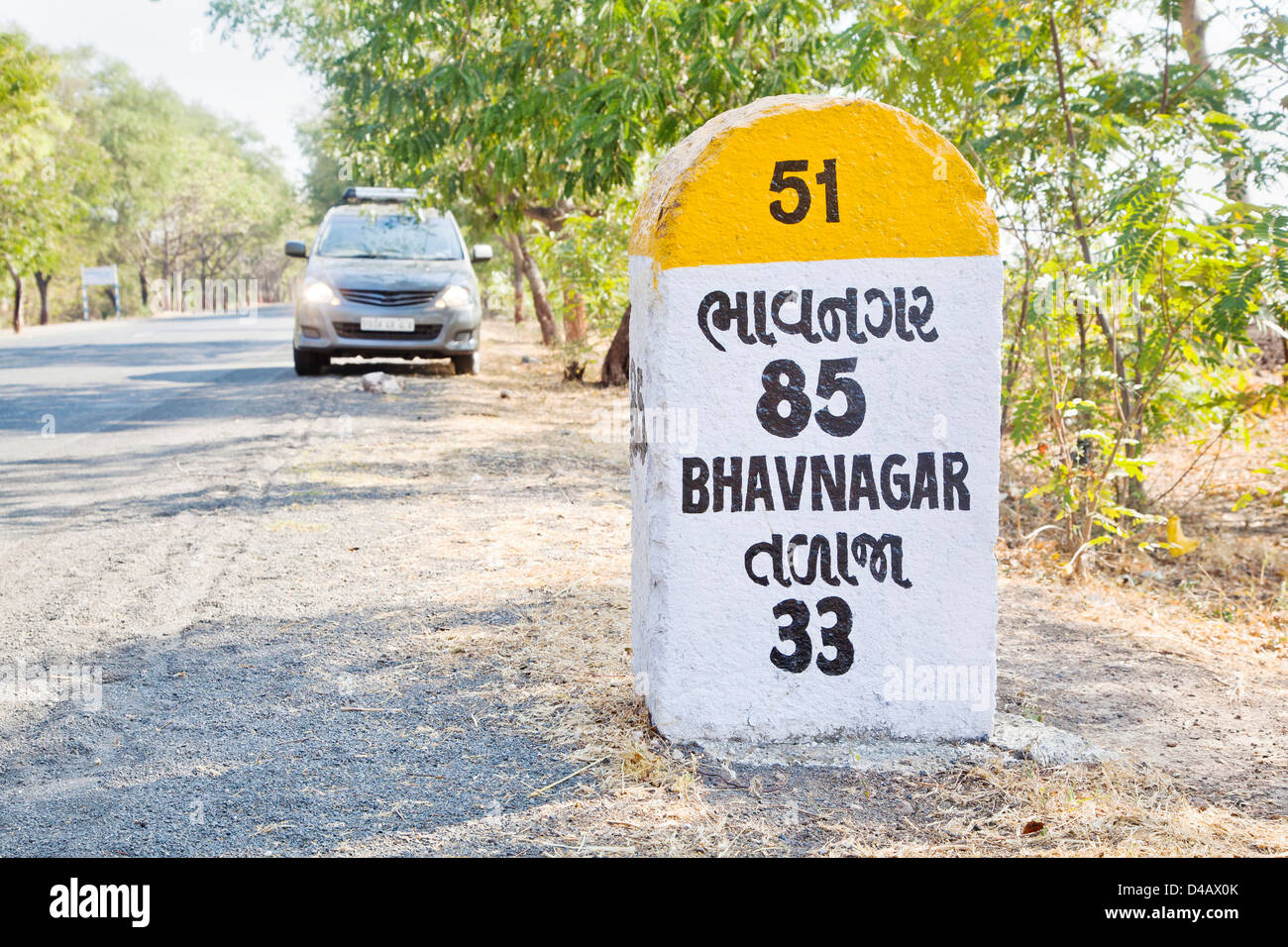 Bhavnagar milestone and land mark on the coastal road to Dwarka a religious town for Hindus. Parked people carrier with head lig Stock Photo