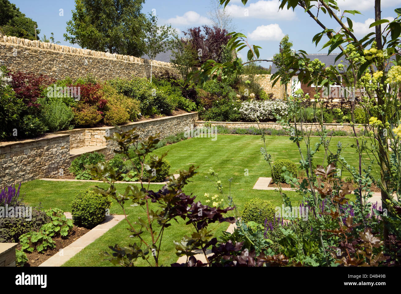 UK gardens. A newly created garden with summer shrubs in borders and new limestone boundary walls. Stock Photo