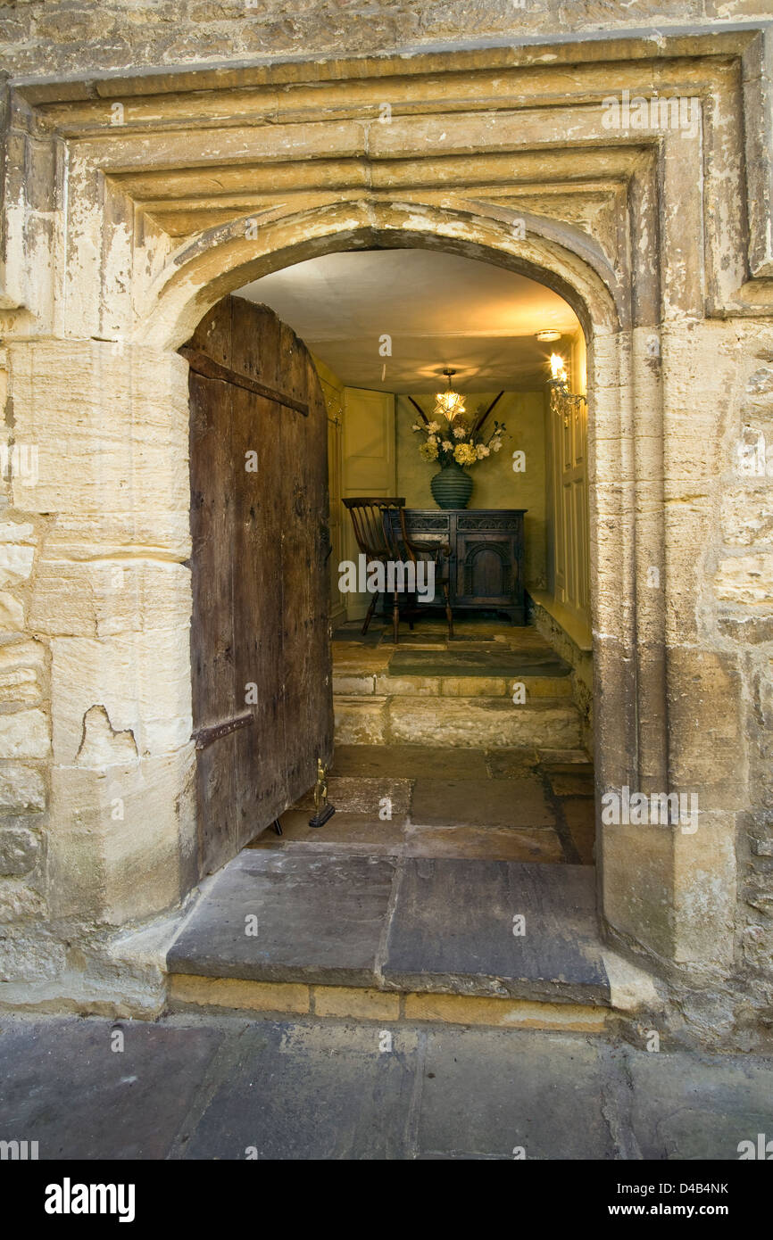 An ancient door opening onto an antique furnished entrance hall interior. Stock Photo