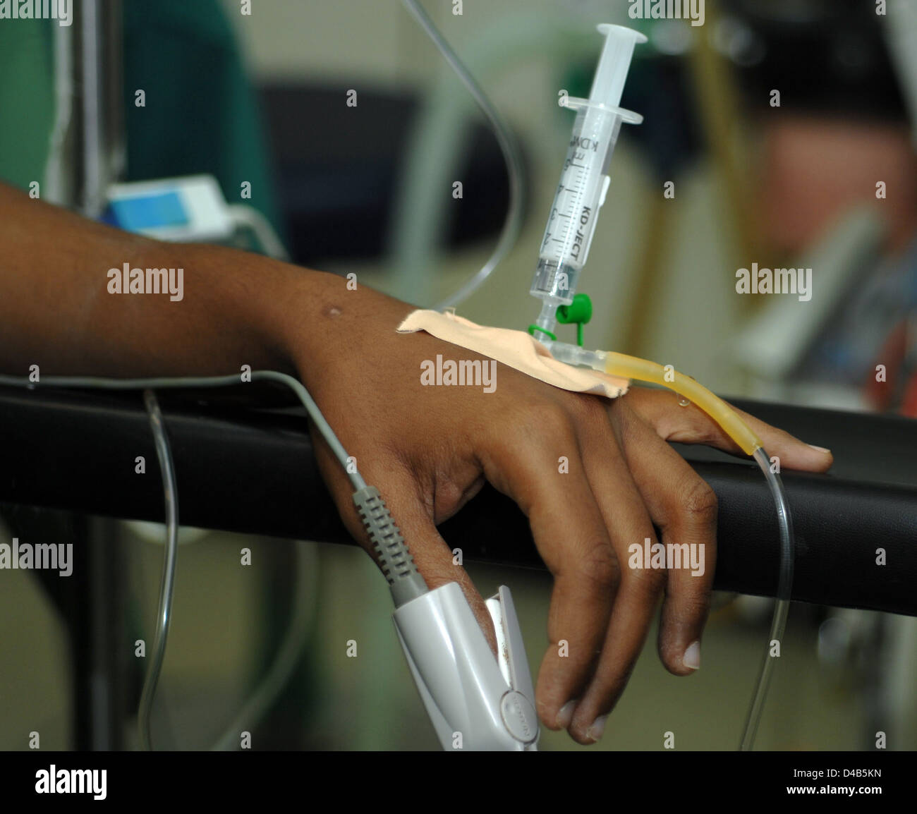 Close up of syringe inserted into catheter attached to patient's hand Stock Photo