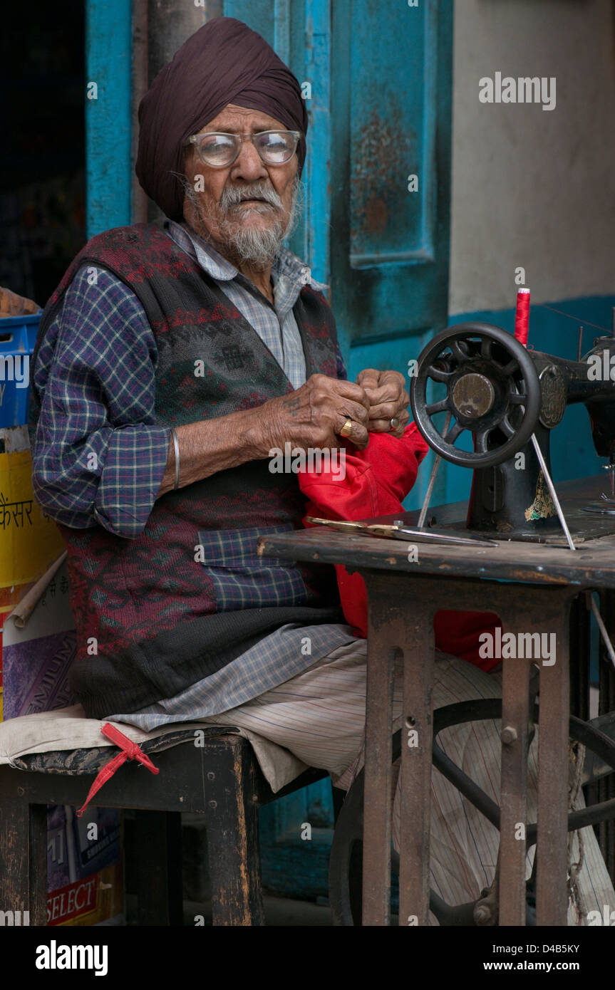 An elderly sikh tailor pauses to look at the camera In Delhi, India Stock Photo