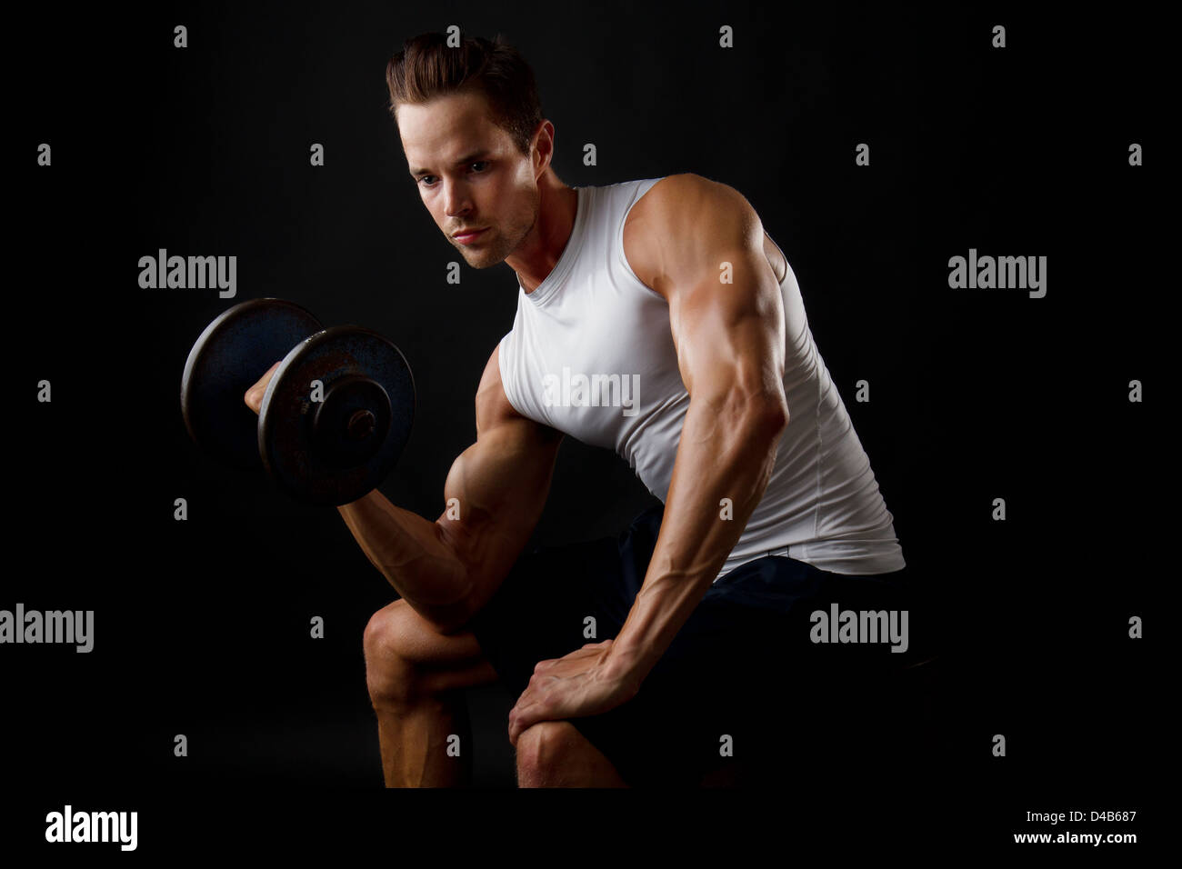 Attractive male doing dumbbell lifts and flexing arm Stock Photo