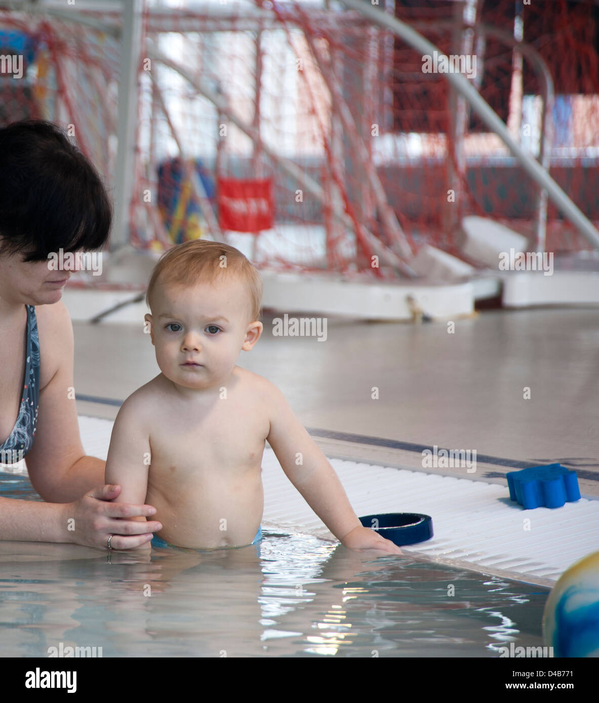 Baby and mother in public swimming pool playing Stock Photo