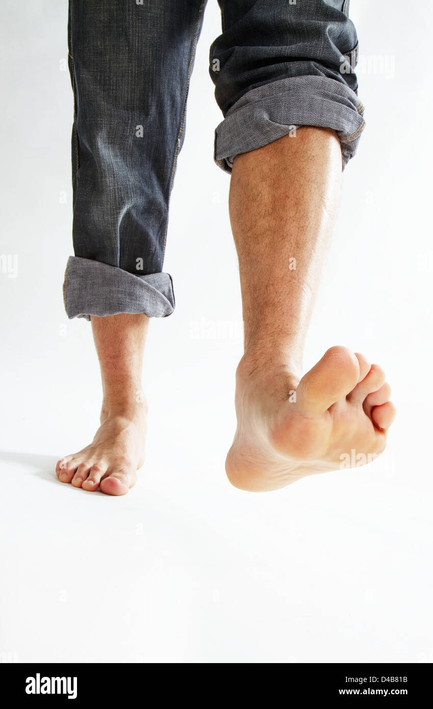 Barefoot man wearing rolled up jeans stepping forward, low section Stock Photo Alamy