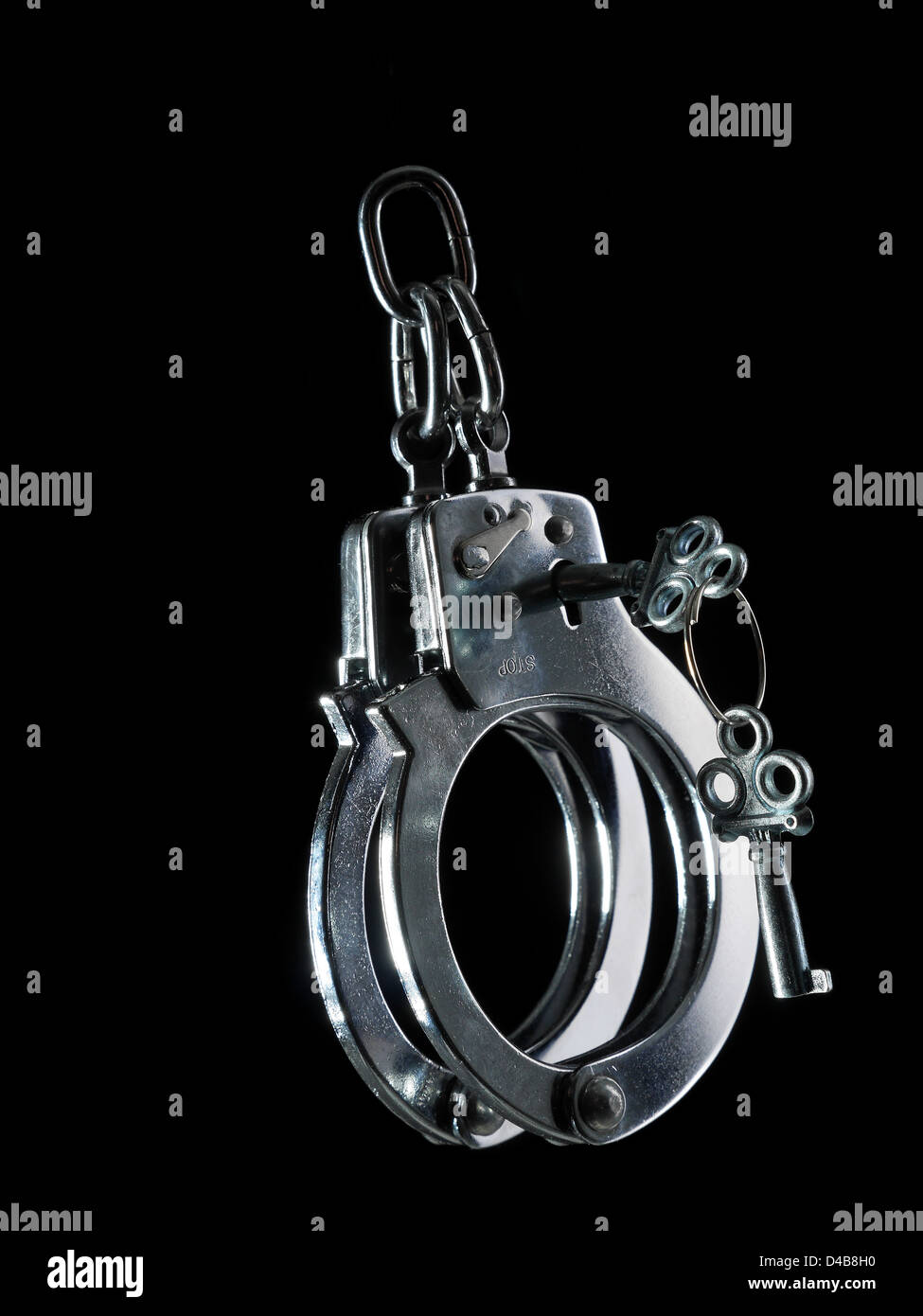 Steel police handcuffs with unlocking keys shot on black background Stock Photo